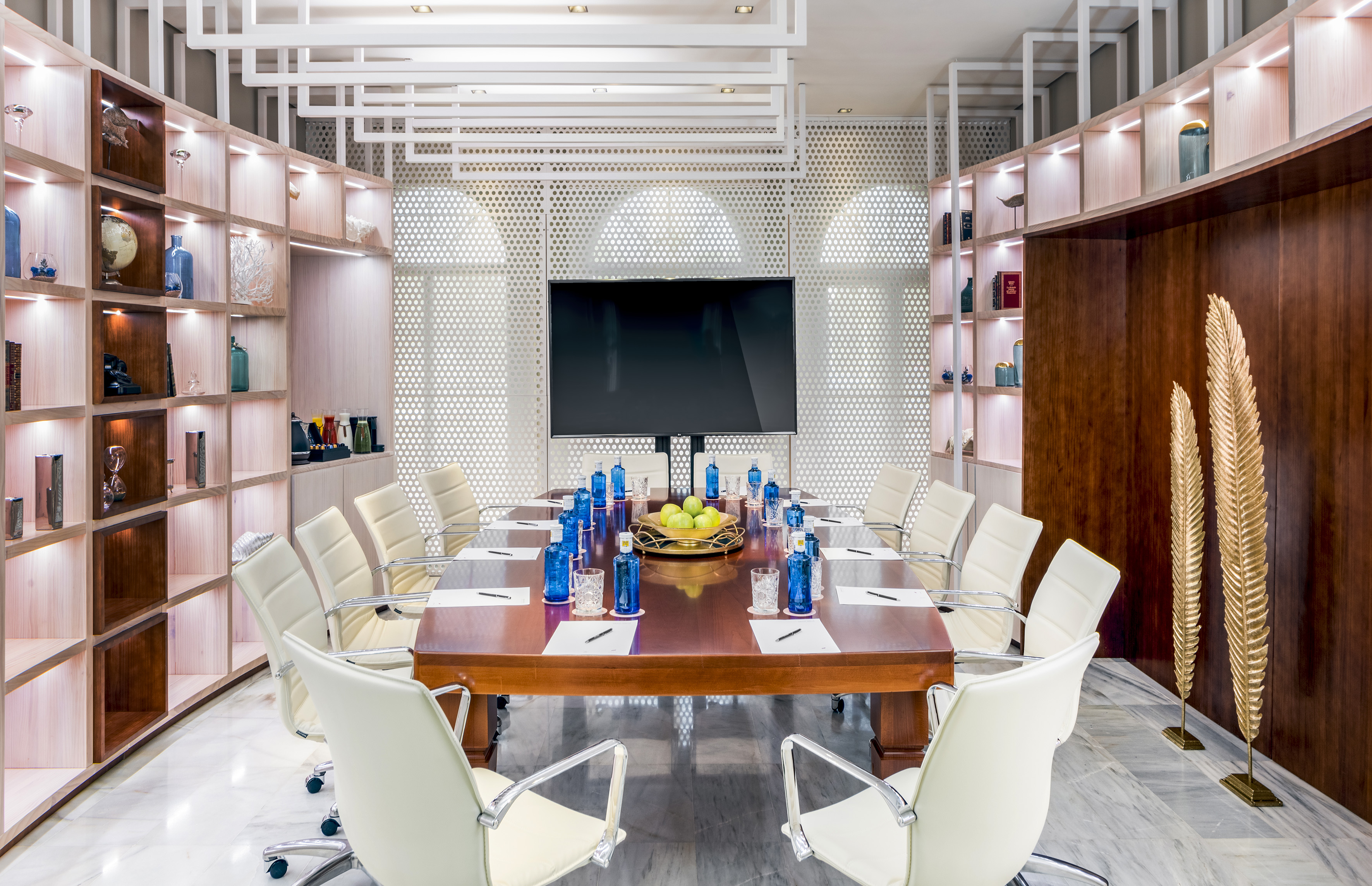Modern conference room with large table, white chairs, TV, and stylish decor.