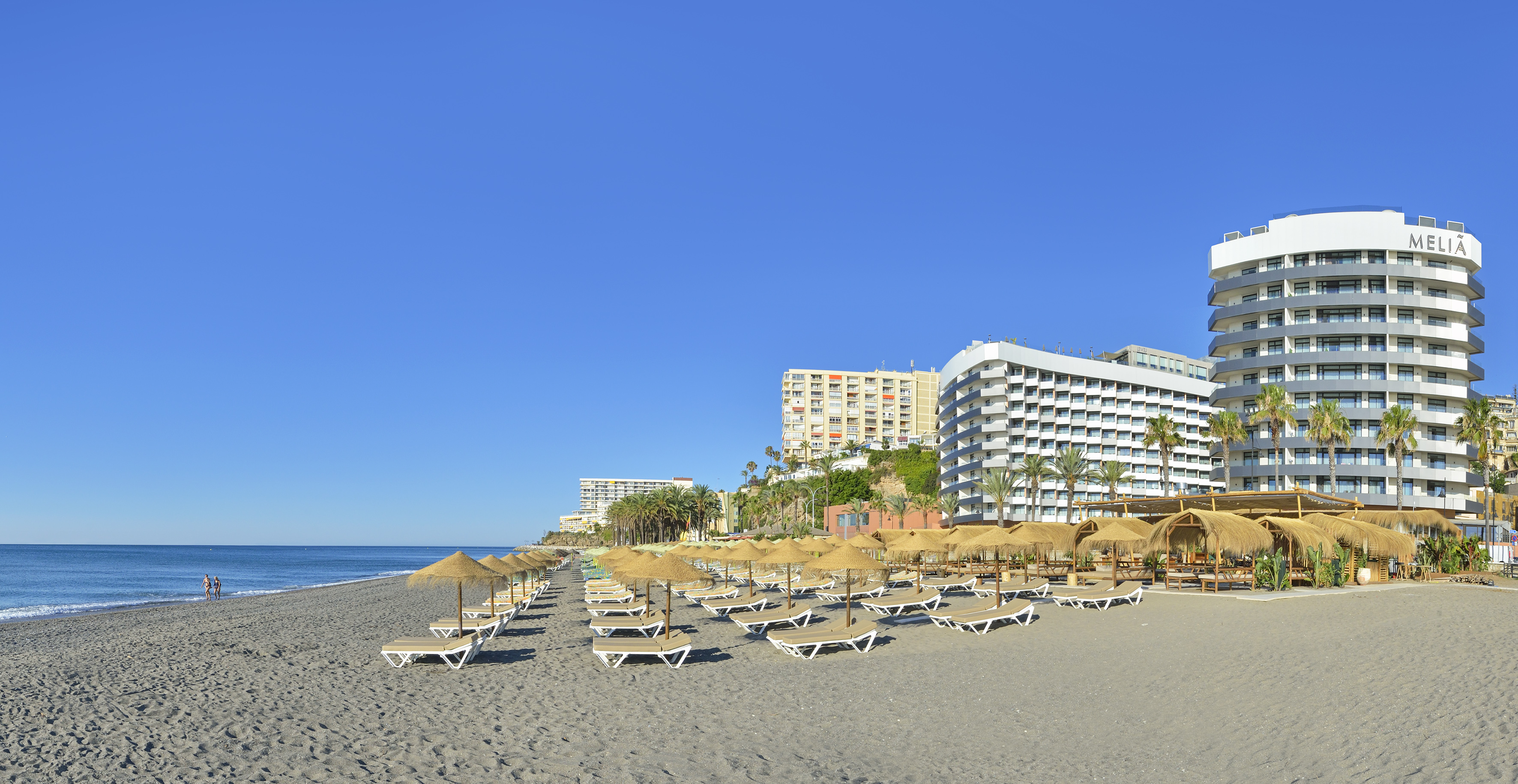 Meliá hotel beach resort with sun loungers, straw umbrellas, and ocean.