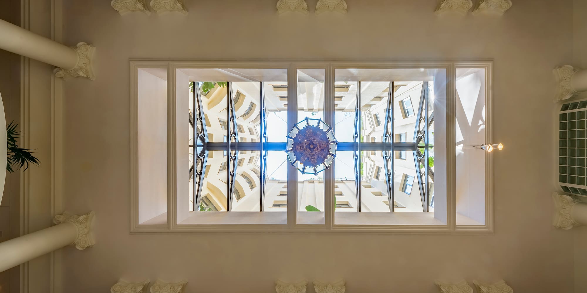 looking up at a ceiling with columns and a chandelier