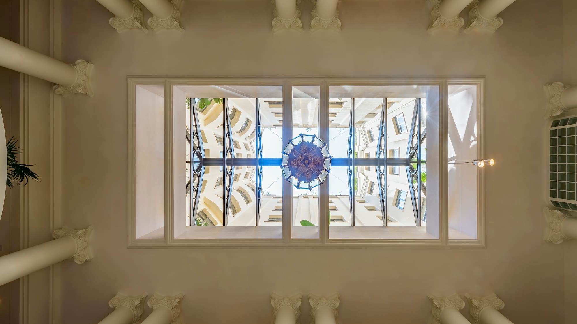 looking up at a ceiling with columns and a chandelier
