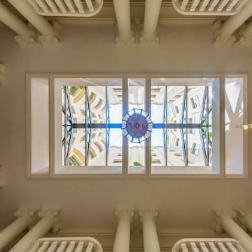 looking up at a ceiling with columns and a chandelier