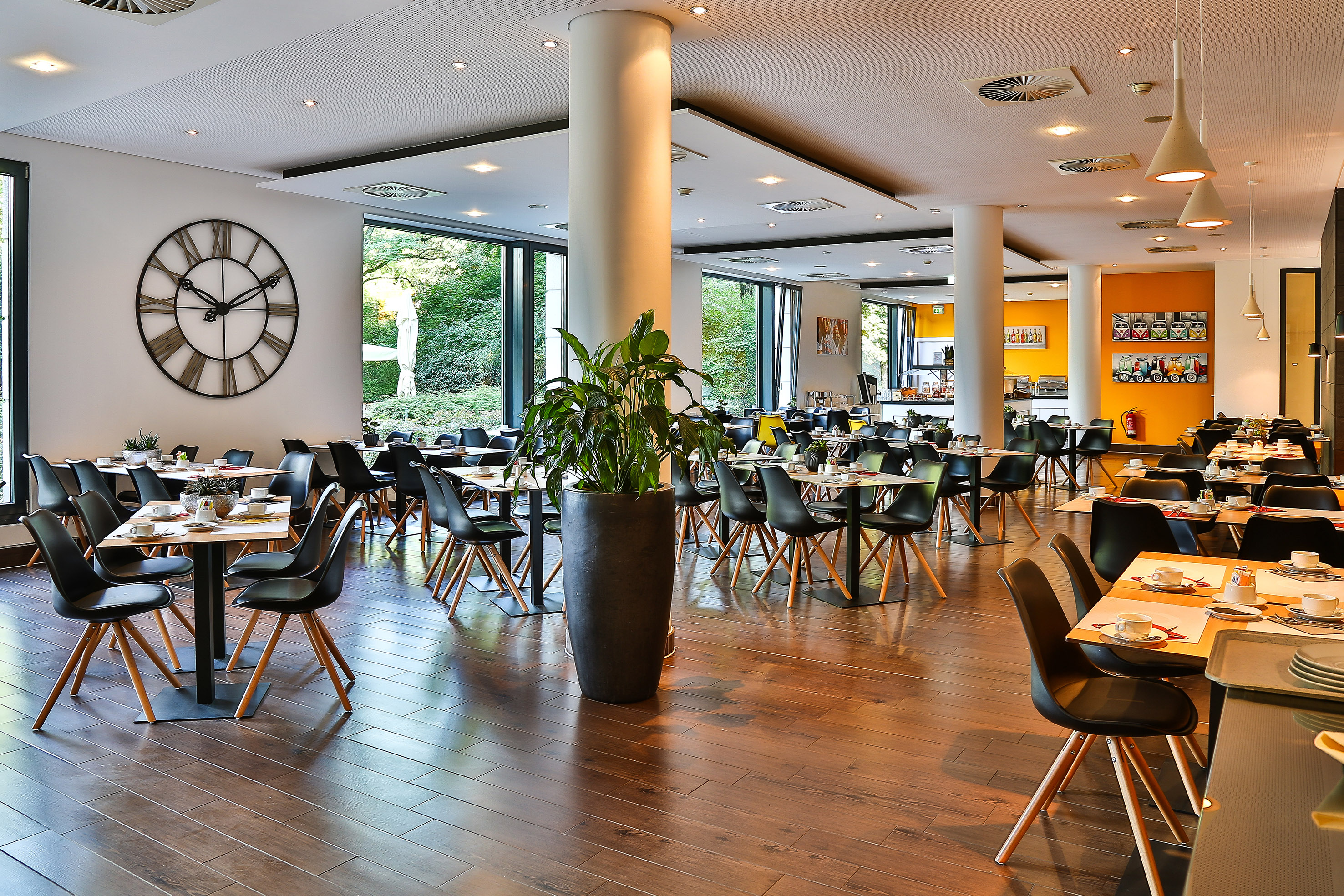 Bright hotel restaurant dining room with modern design and large windows.