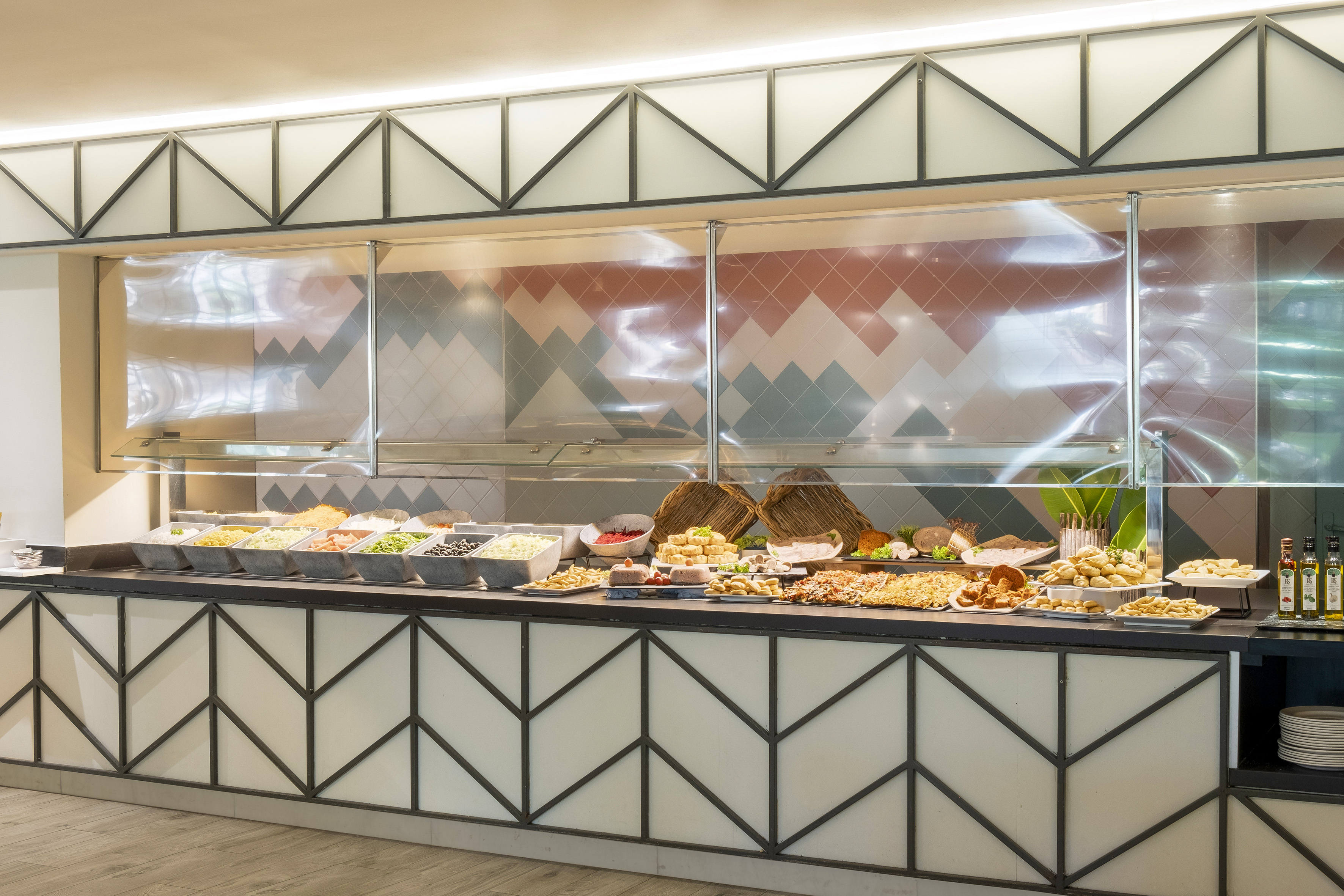 Hotel buffet with assorted salads, appetizers, and snacks behind a sneeze guard.