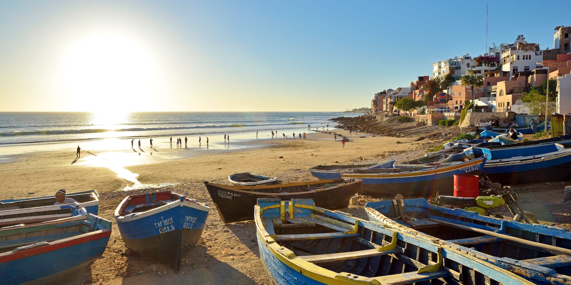 boats on a beach with buildings and people in the background
