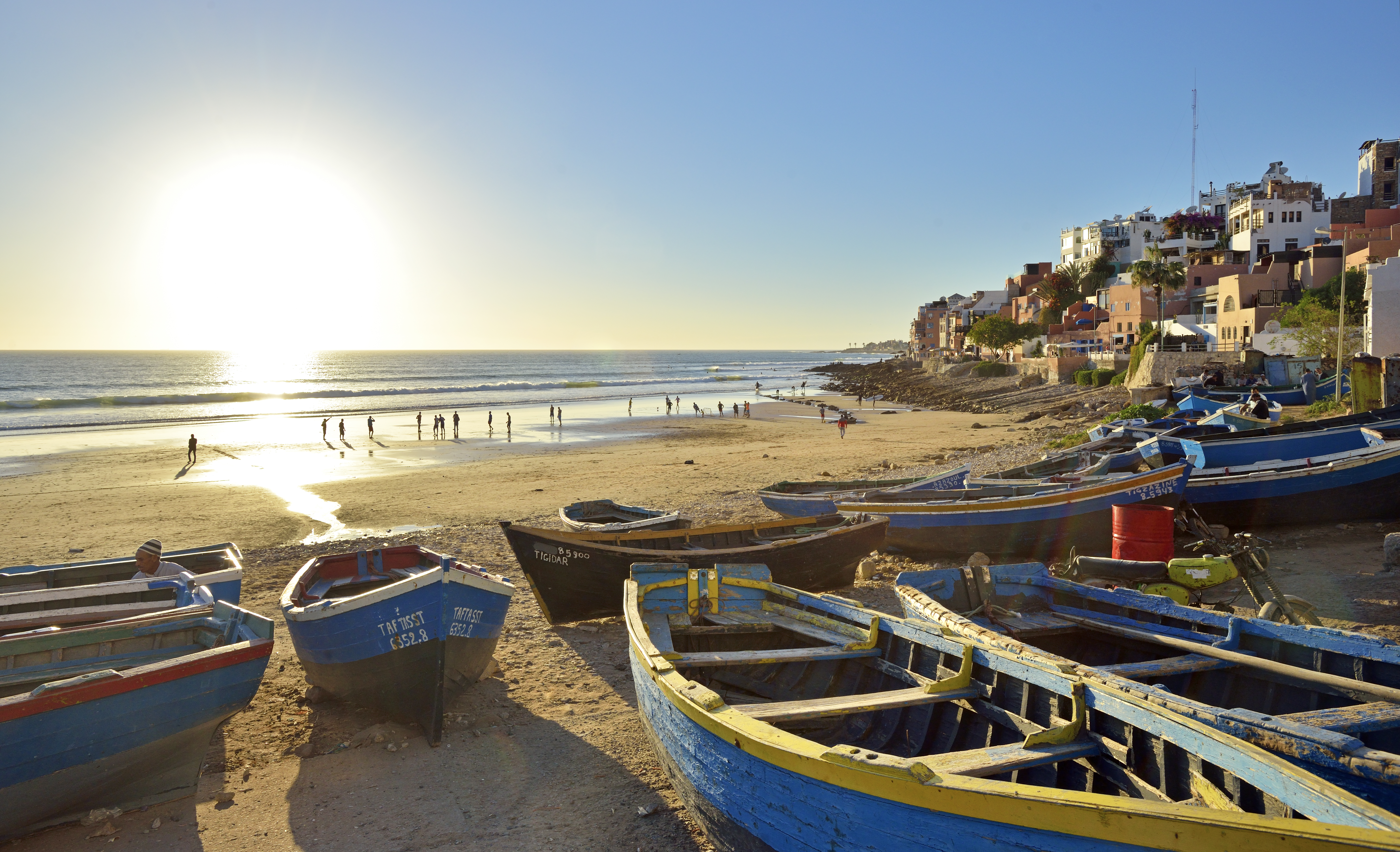 boats on a beach with buildings and people in the background