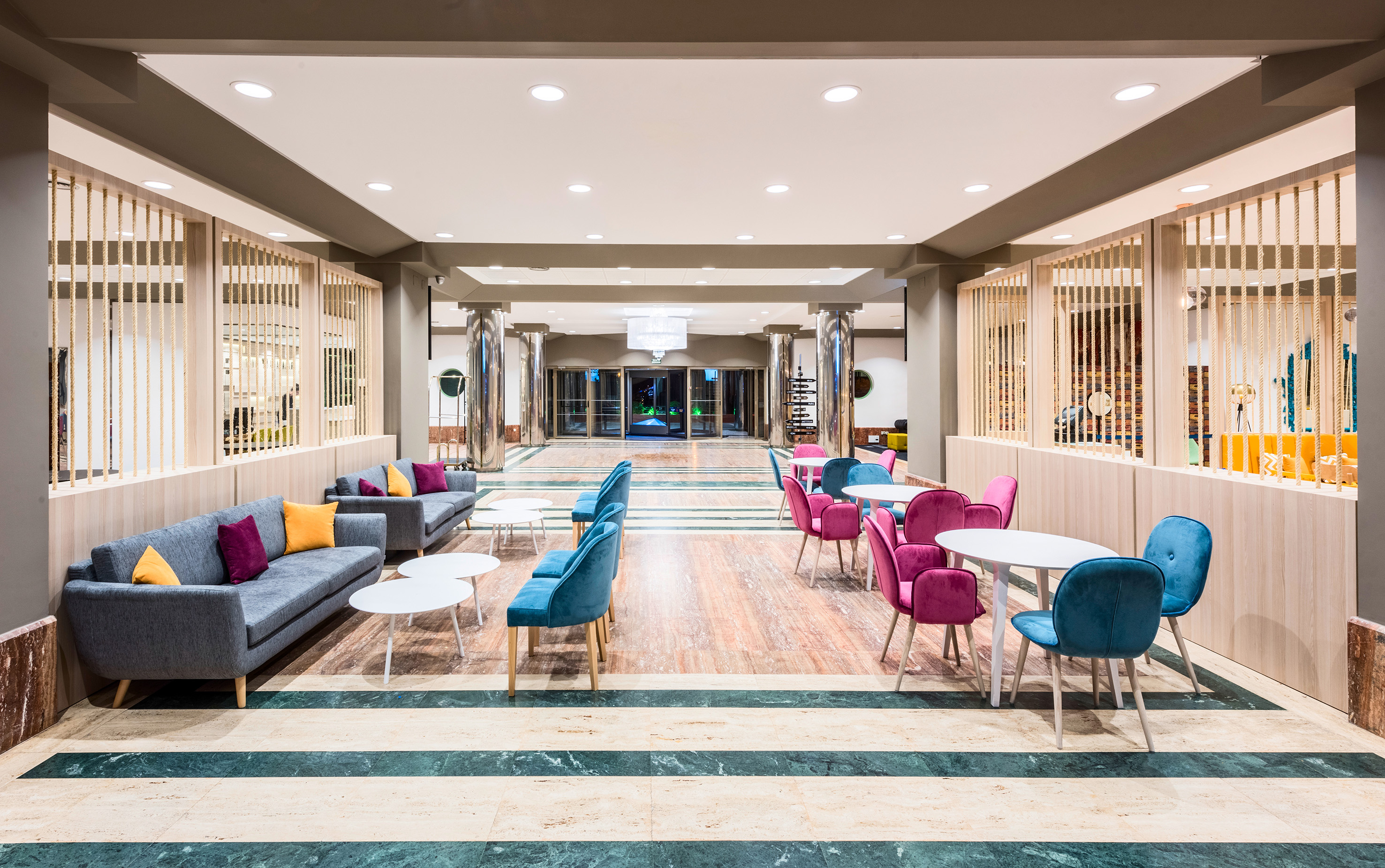 Bright hotel lobby lounge with modern colorful seating and elegant striped floor.