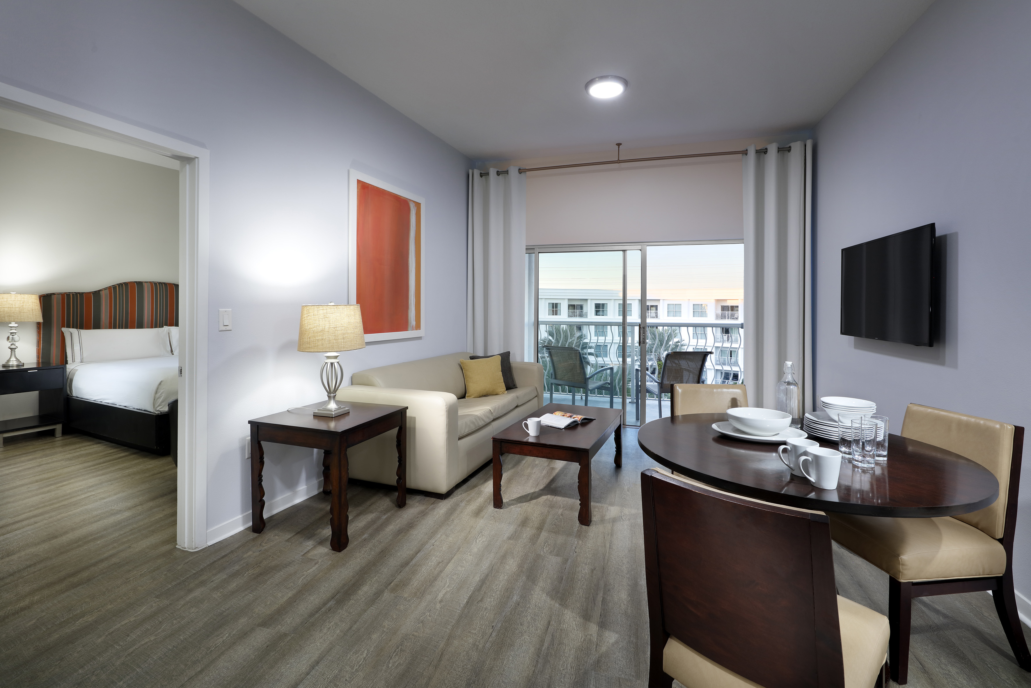 Furnished suite with living room, dining area, bedroom, and balcony.