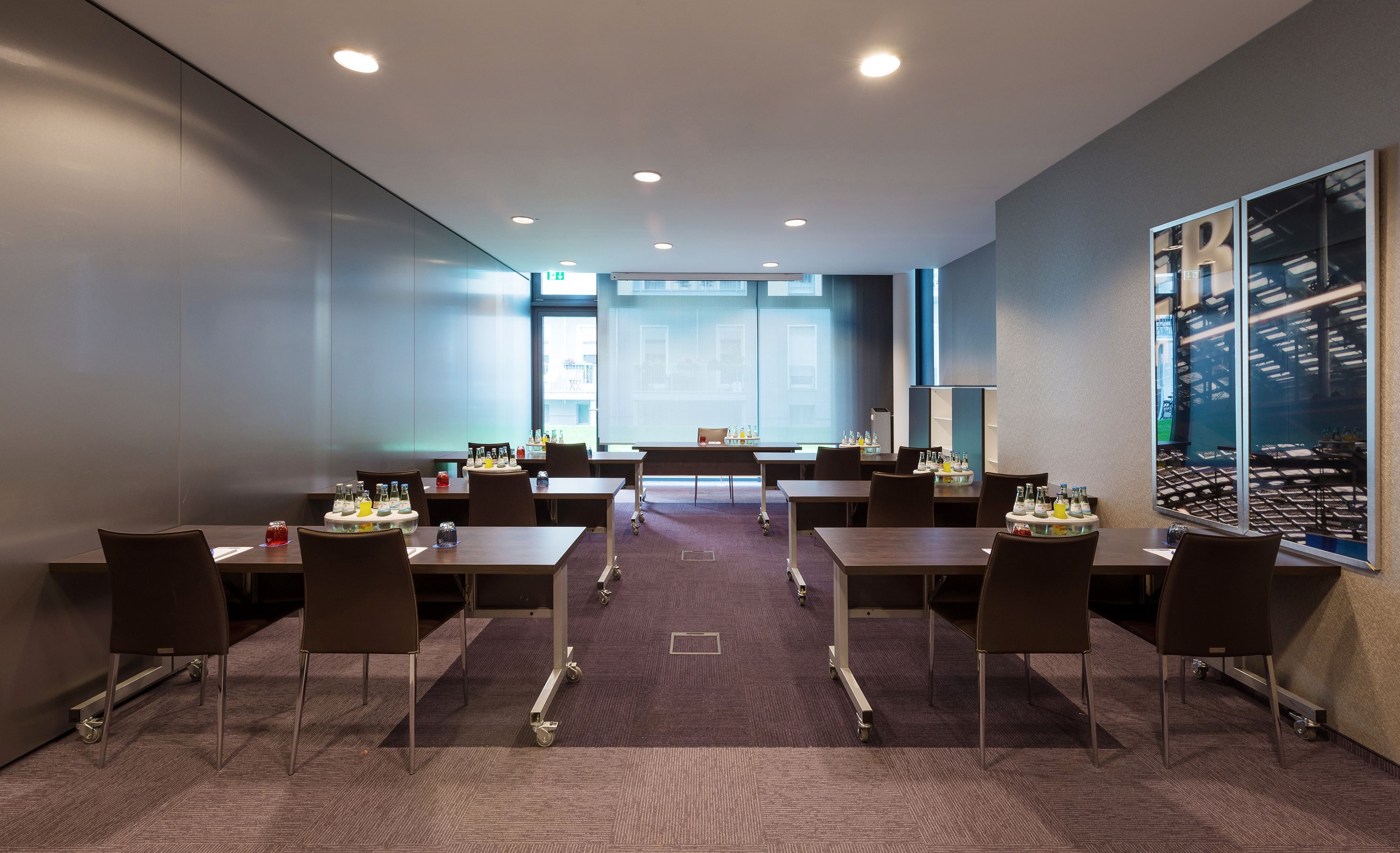 Modern conference room with individual tables, chairs, and refreshments.
