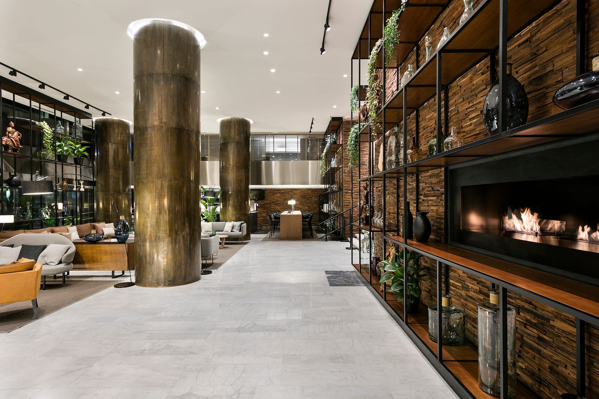 Modern hotel lobby with lounge seating, marble floor, and decorative fireplace.