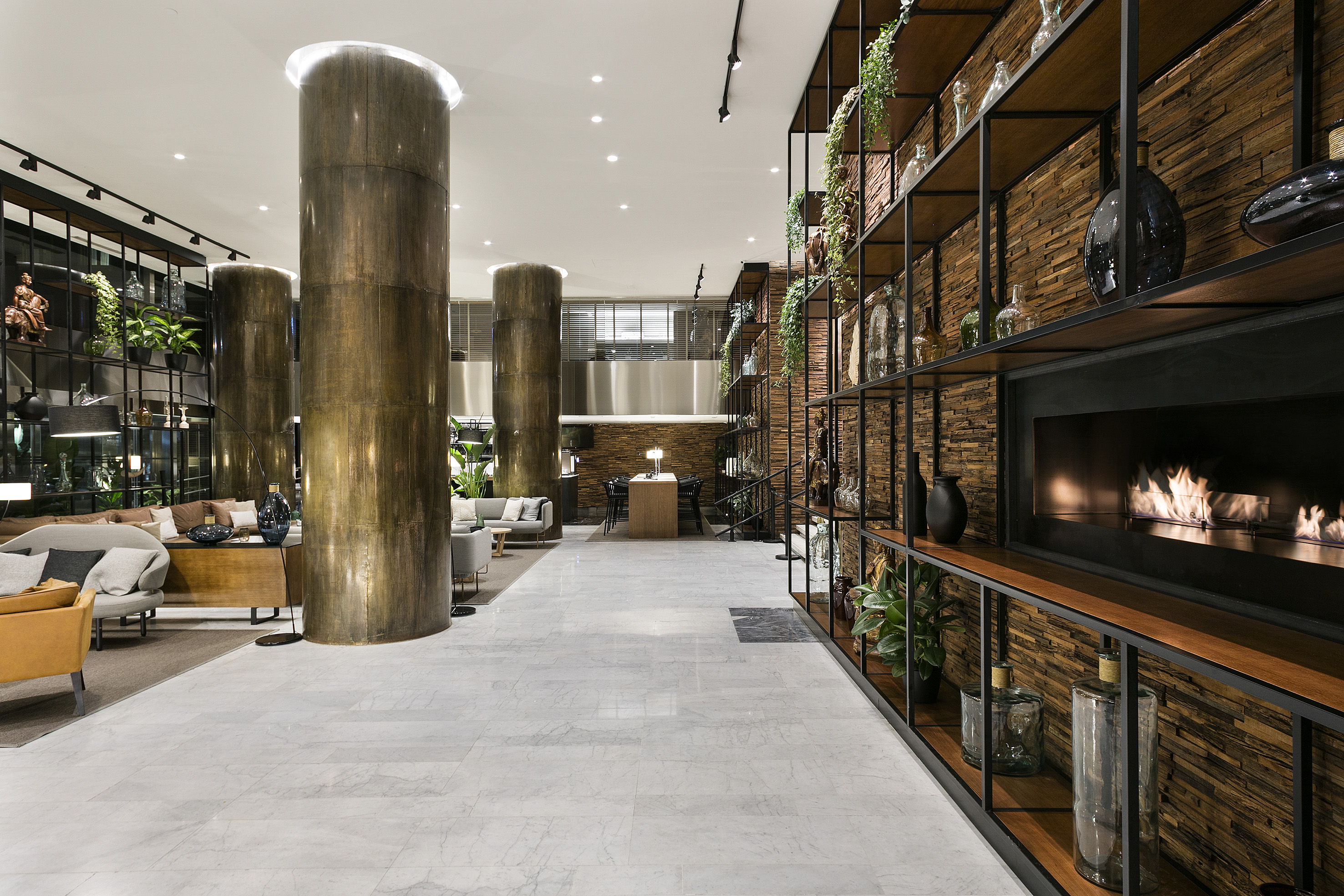 Modern hotel lobby with lounge seating, marble floor, and decorative fireplace.