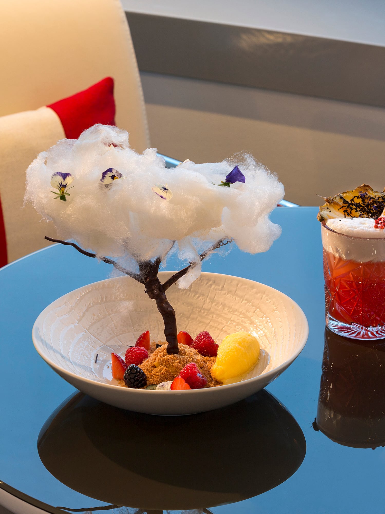 a bowl of fruit and a glass of liquid on a table