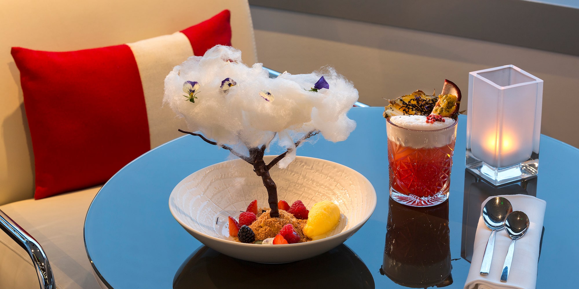 a bowl of fruit and a glass of liquid on a table