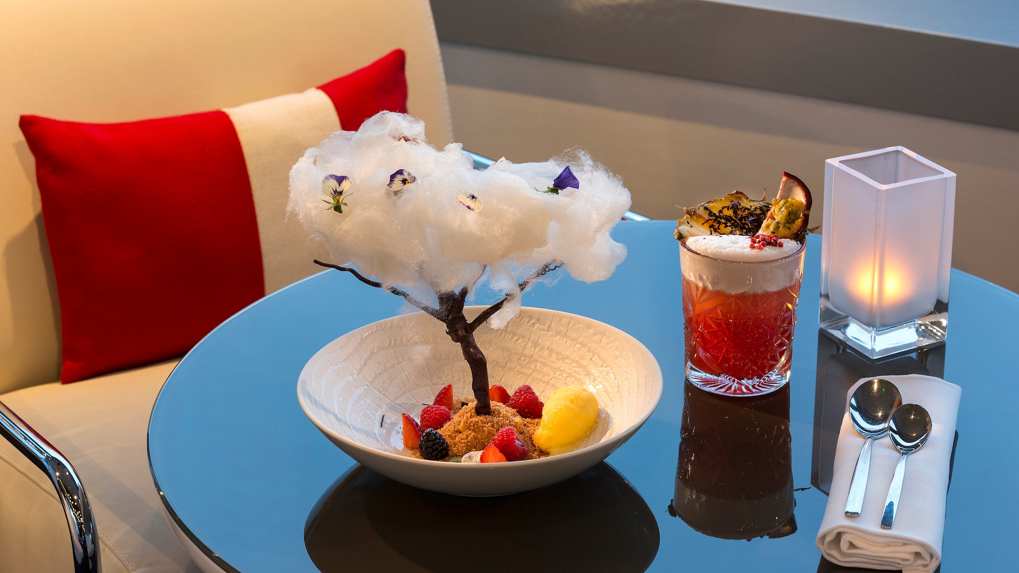 a bowl of fruit and a glass of liquid on a table
