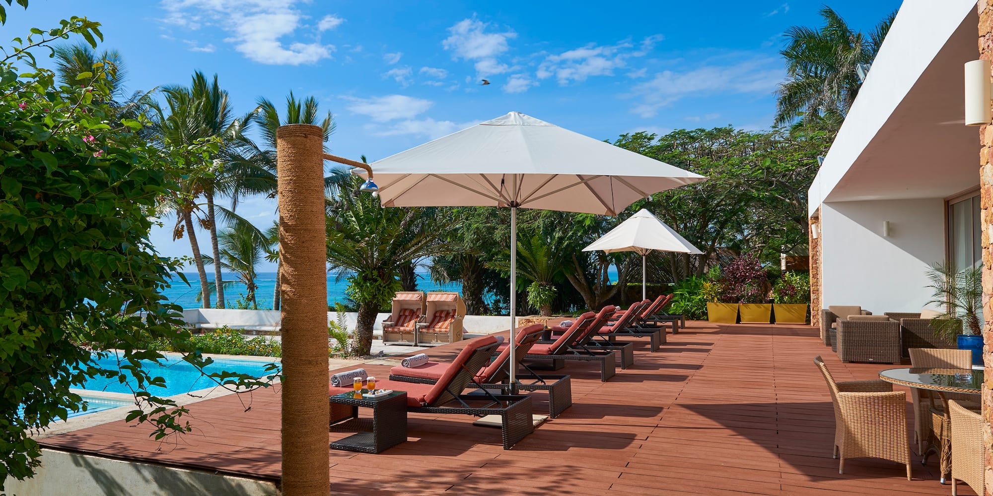 a deck with chairs and umbrellas by a pool