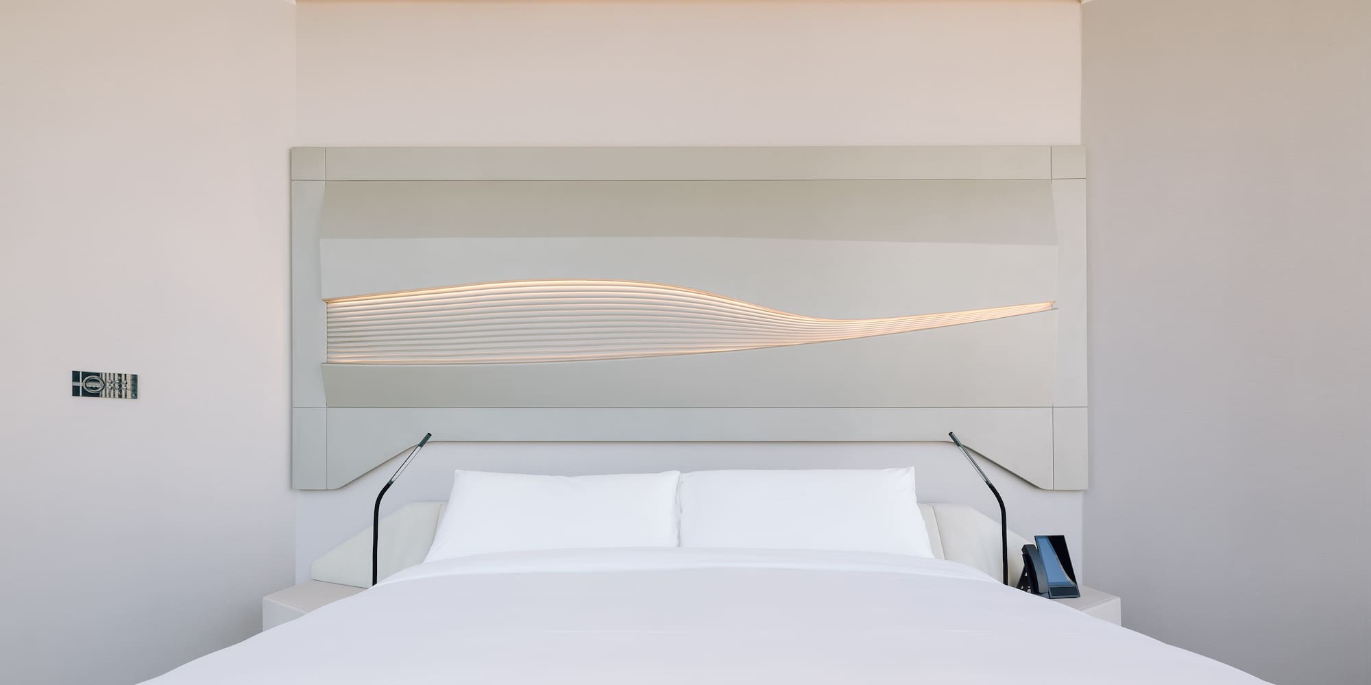 a bed with a white bedding and a white wall