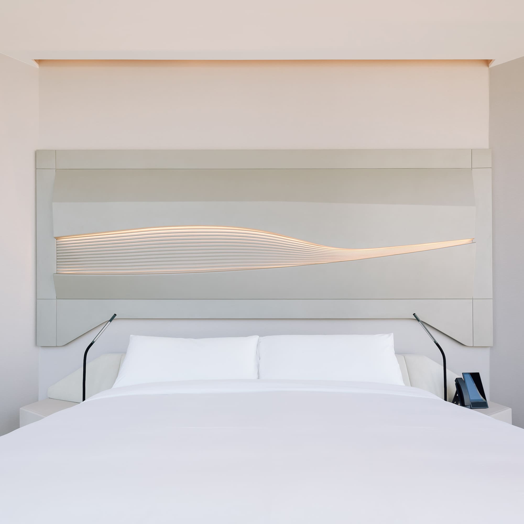 a bed with a white bedding and a white wall