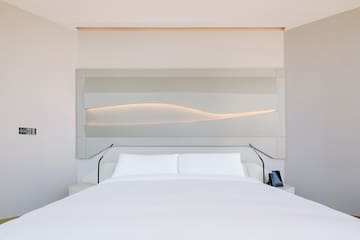 a bed with a white bedding and a white wall