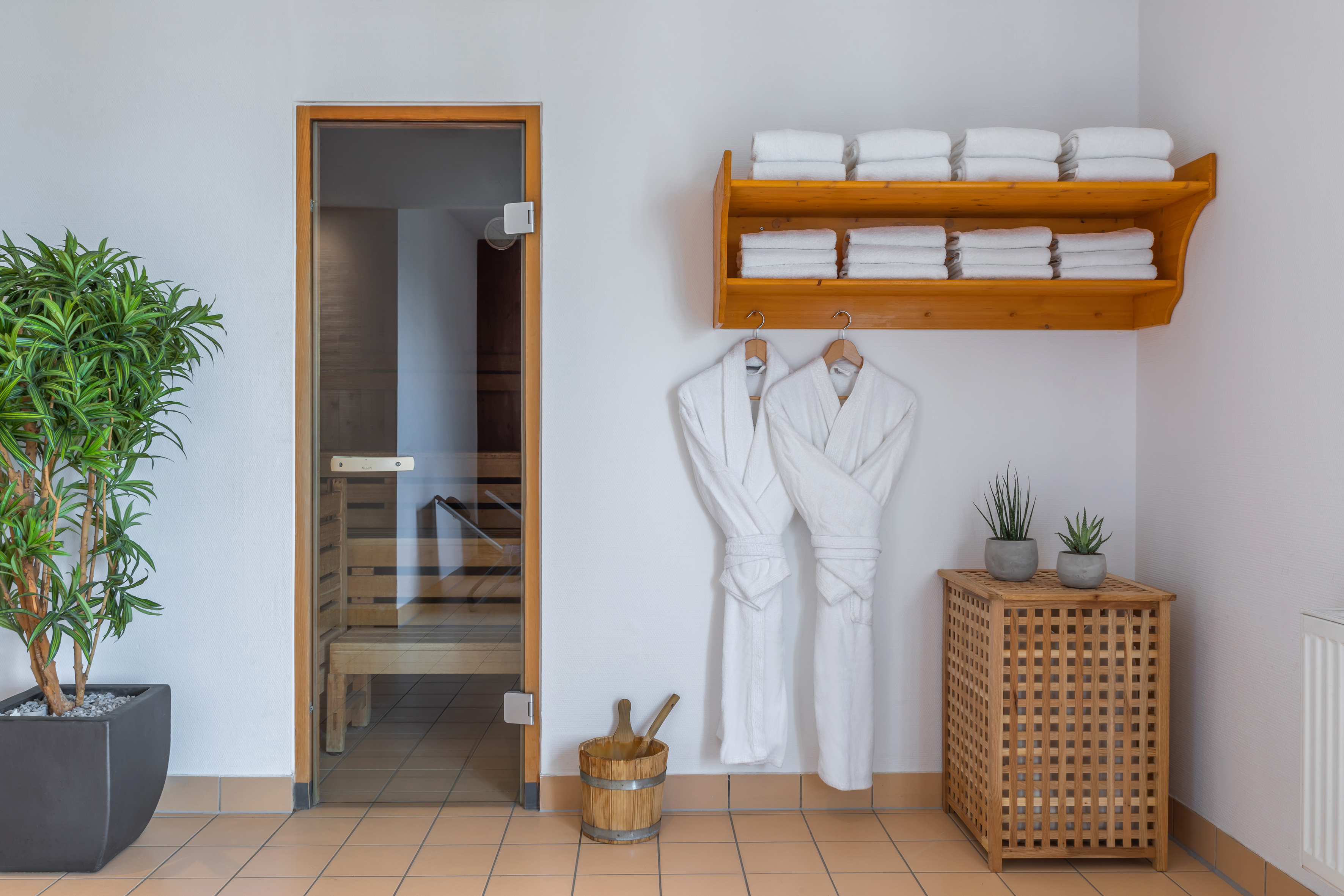 Spa sauna area with glass door, fresh towels, white bathrobes, and plants. - Hotel Münster Kongresscenter Affiliated by Meliá, ミュンスター