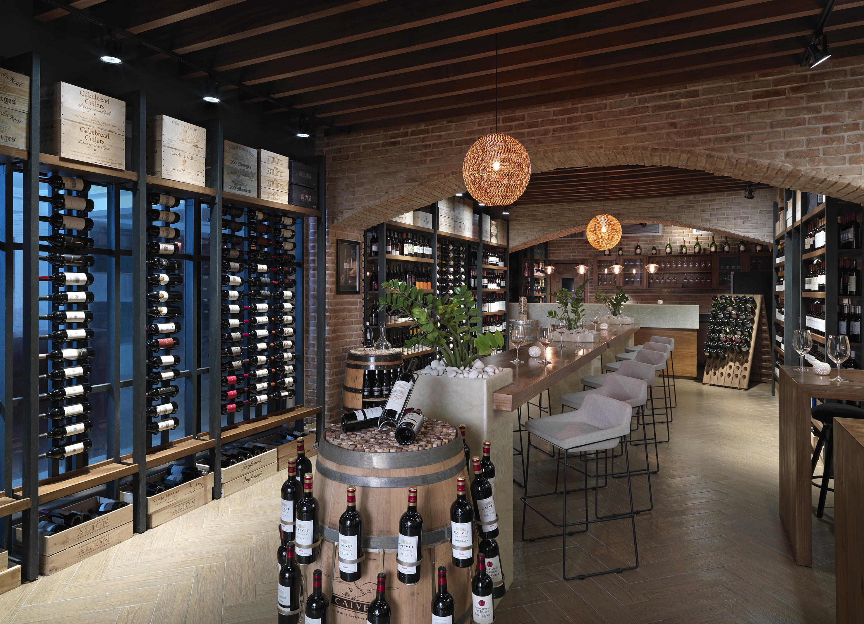 Wine cellar with brick arches, extensive wine racks, tasting bar, and decorative barrels.