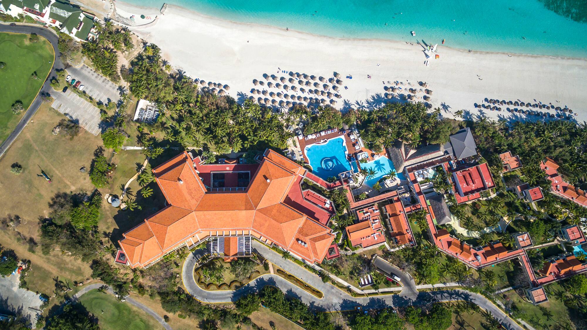 a large building with a pool and trees on a beach