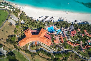 a large building with a pool and trees on a beach