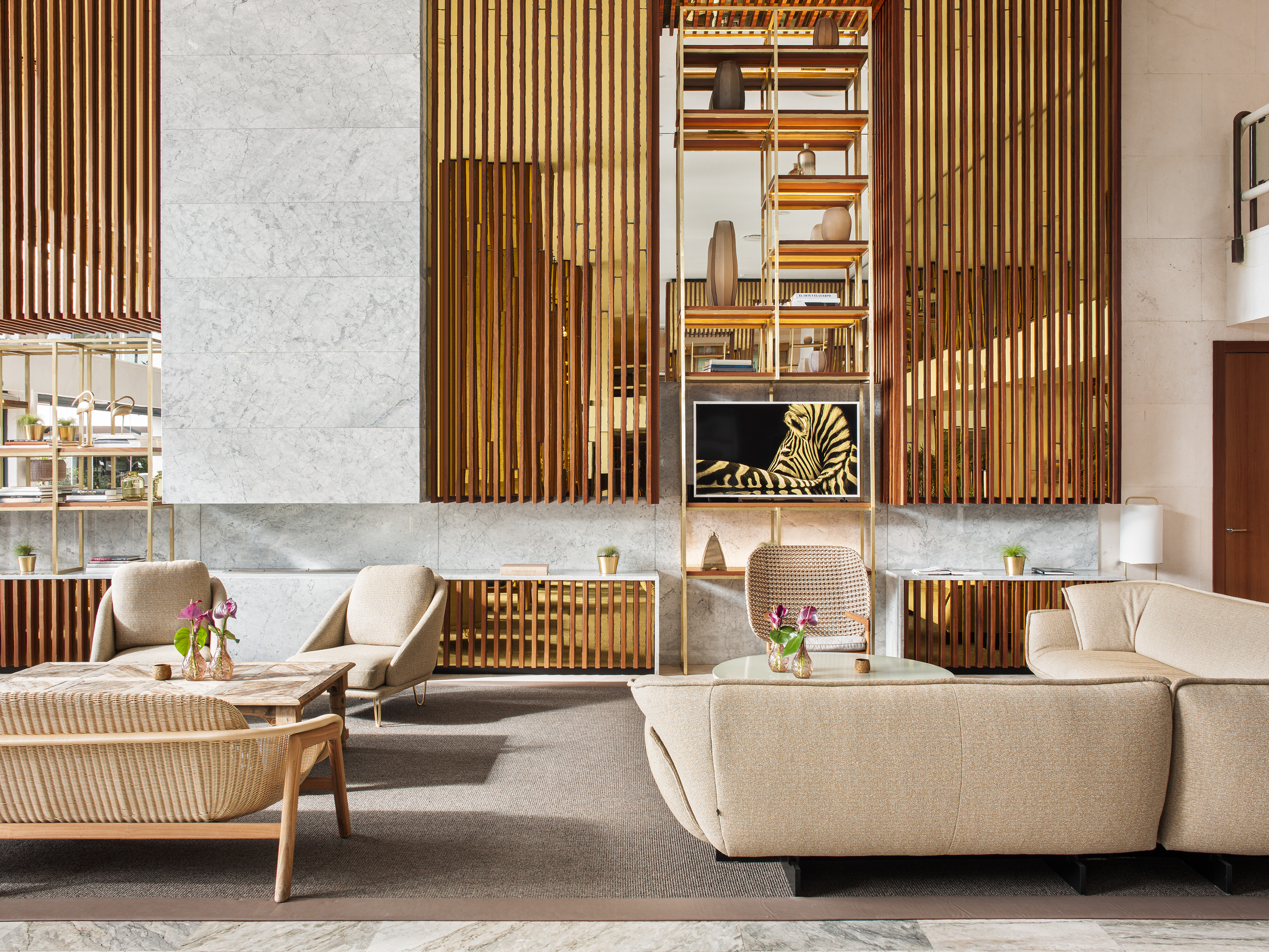 Modern hotel lobby lounge with beige furniture, marble, and wood slat accents.