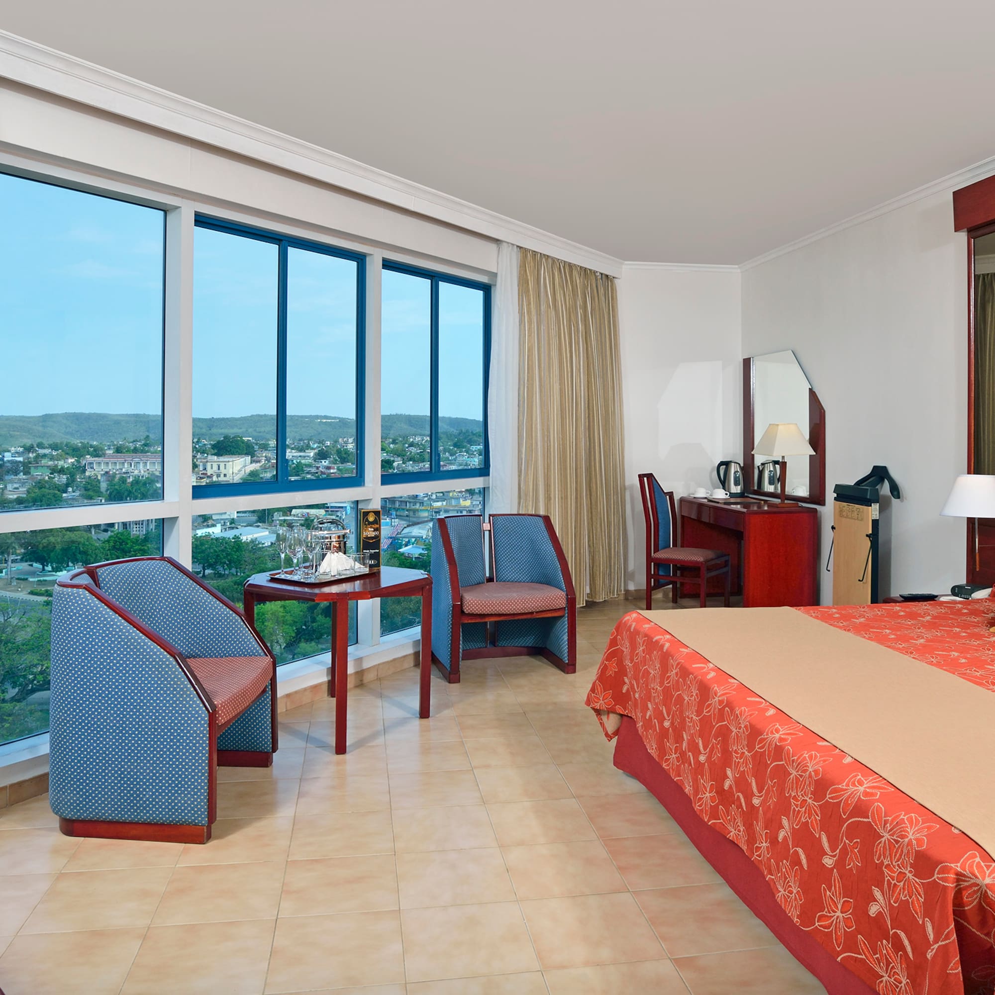 a room with a bed and chairs and a large window