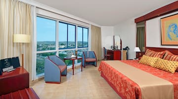 a room with a bed and chairs and a large window