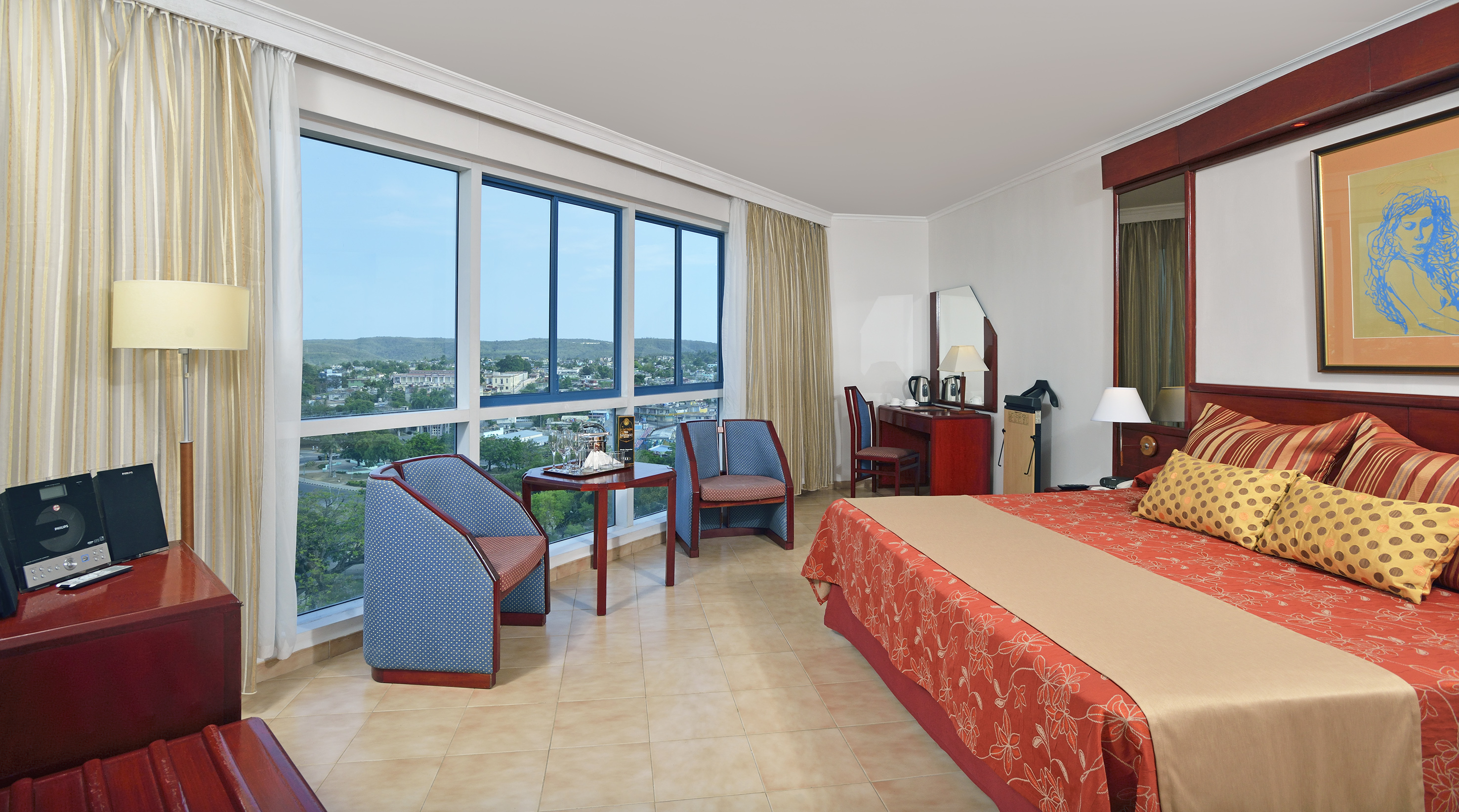 a room with a bed and chairs and a large window