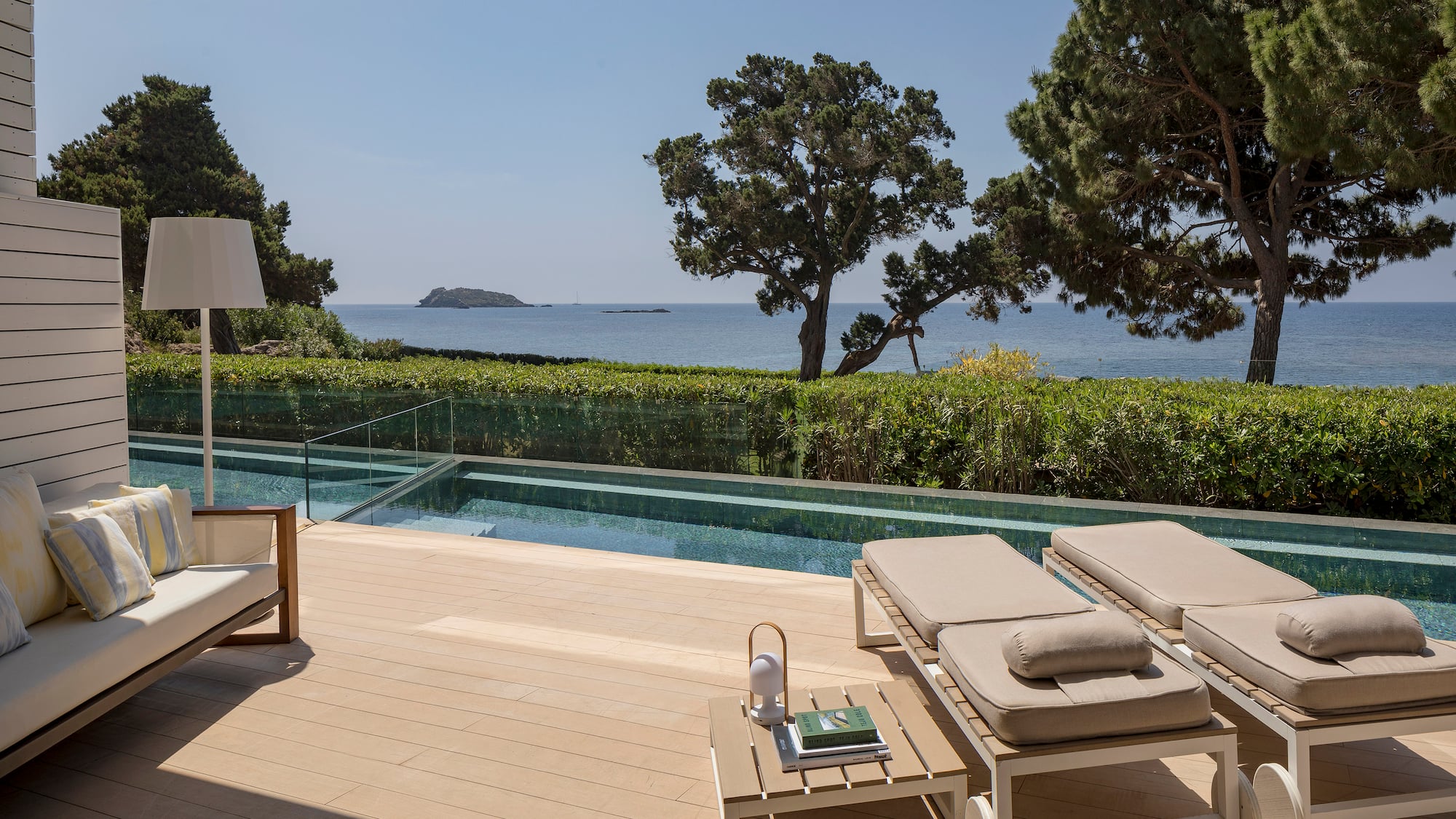 a deck with chairs and a pool overlooking the ocean