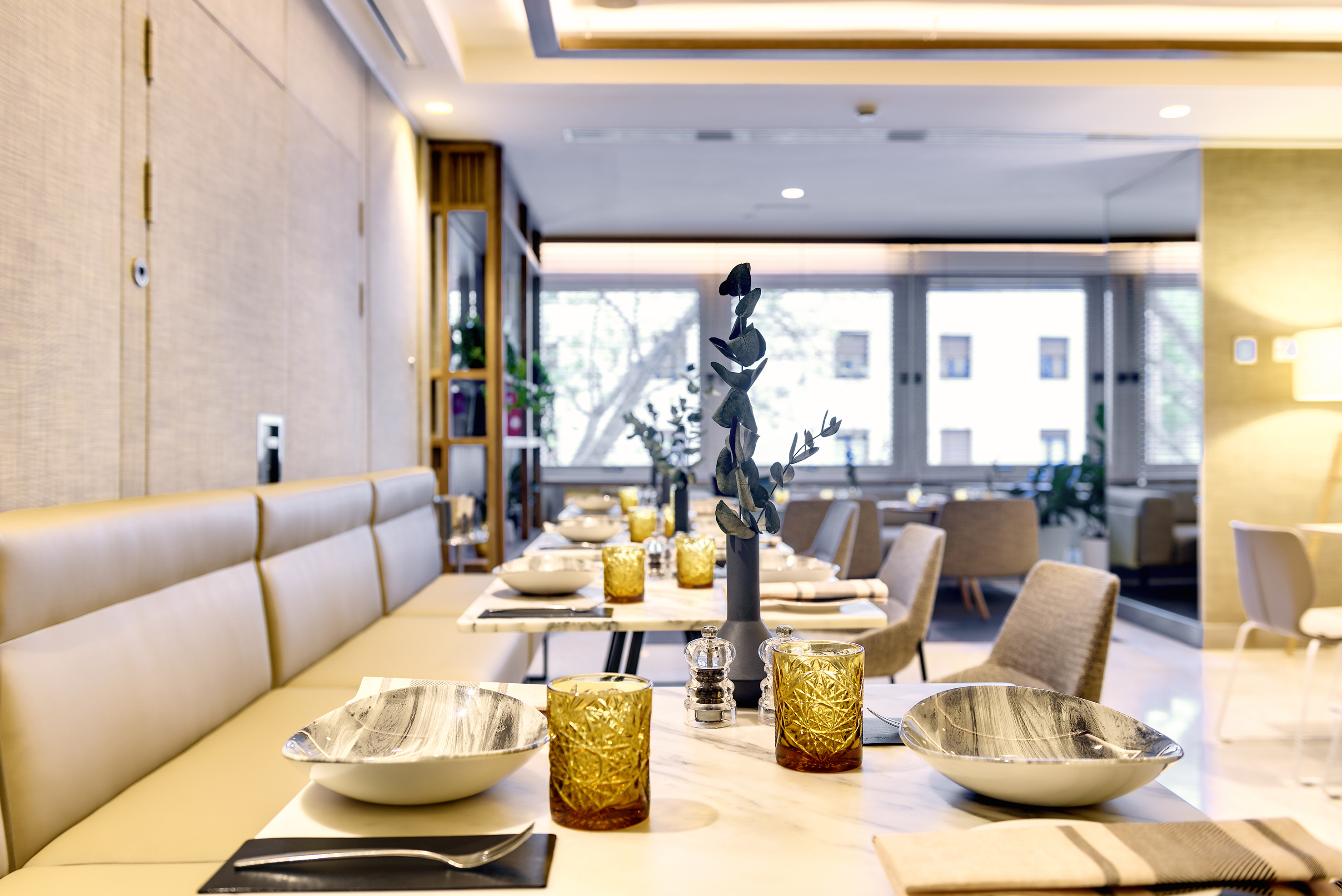 Elegant hotel restaurant dining area with set tables and bench seating.