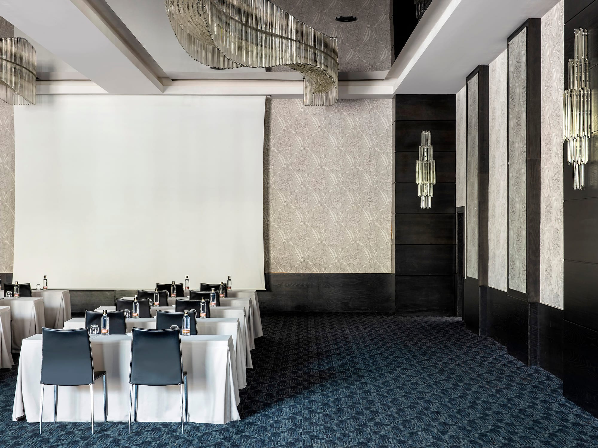 a room with a white screen and tables and chairs