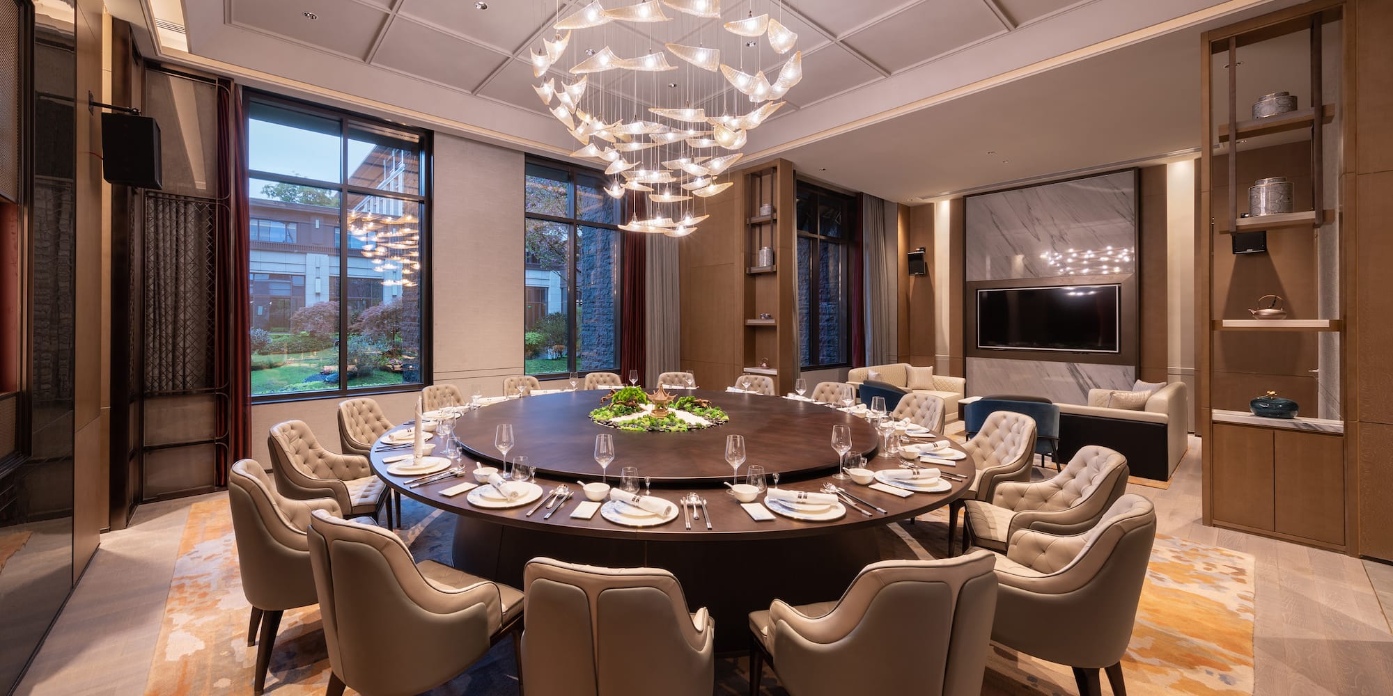 a large round table with plates and chairs in a room with a television