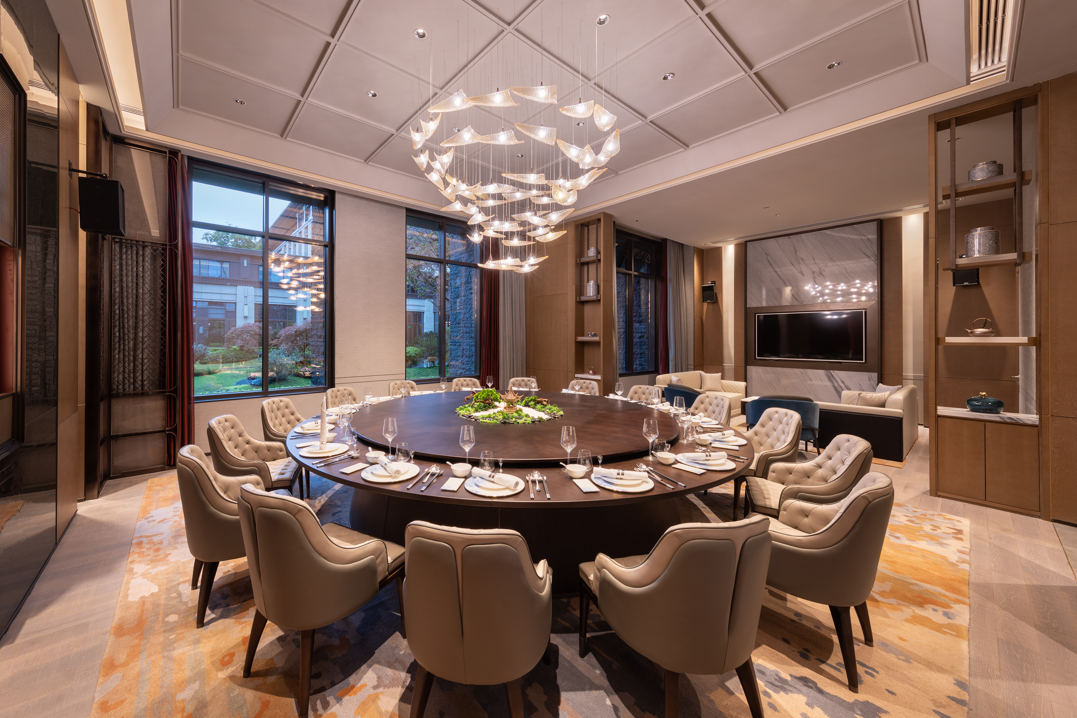 a large round table with plates and chairs in a room with a television