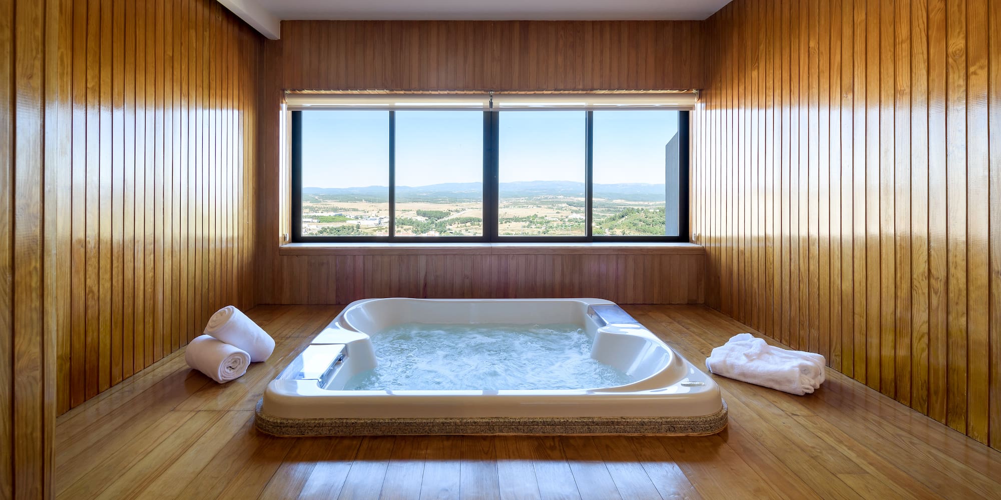 a large hot tub in a room with wood walls and windows