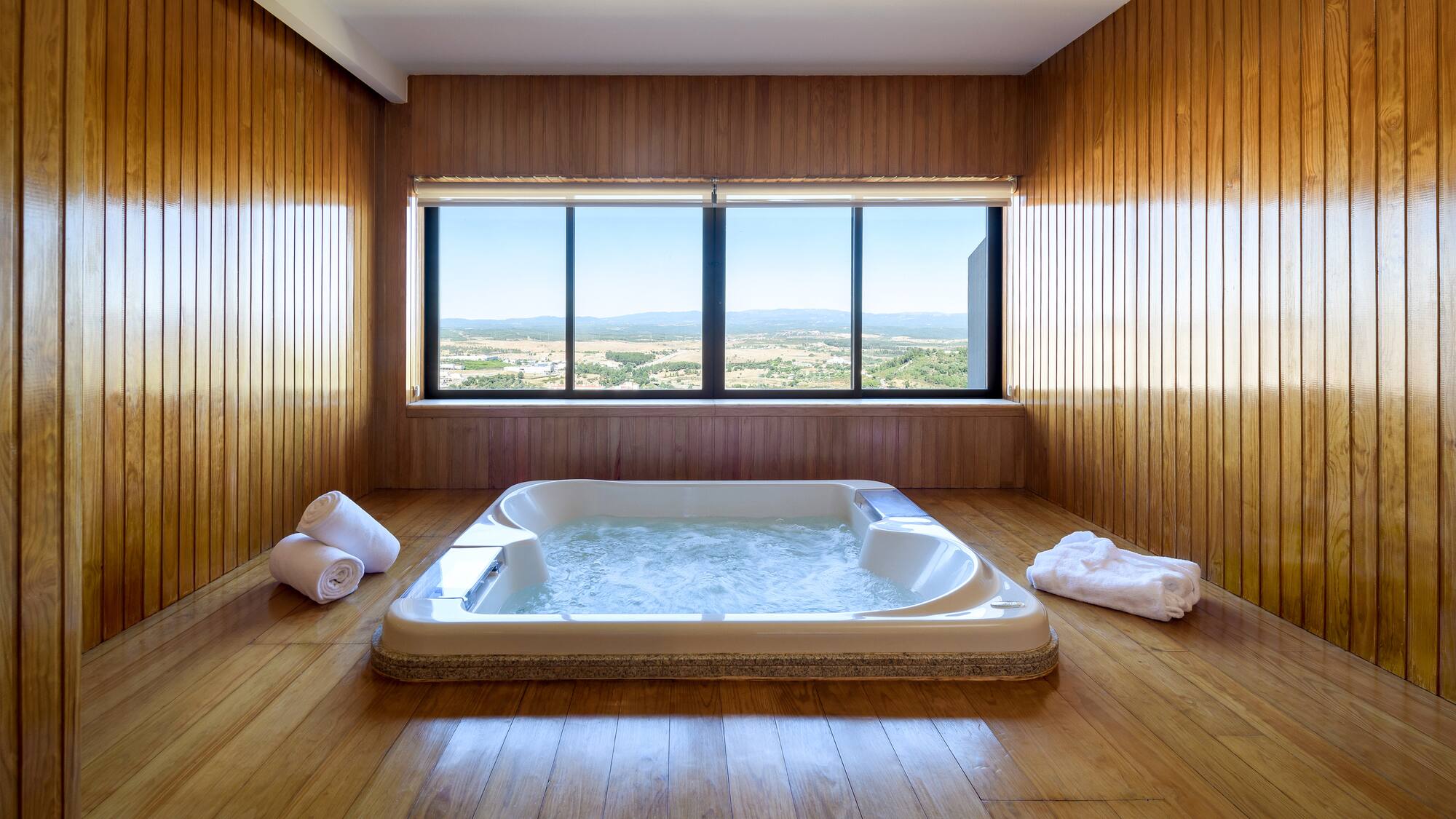 a large hot tub in a room with wood walls and windows