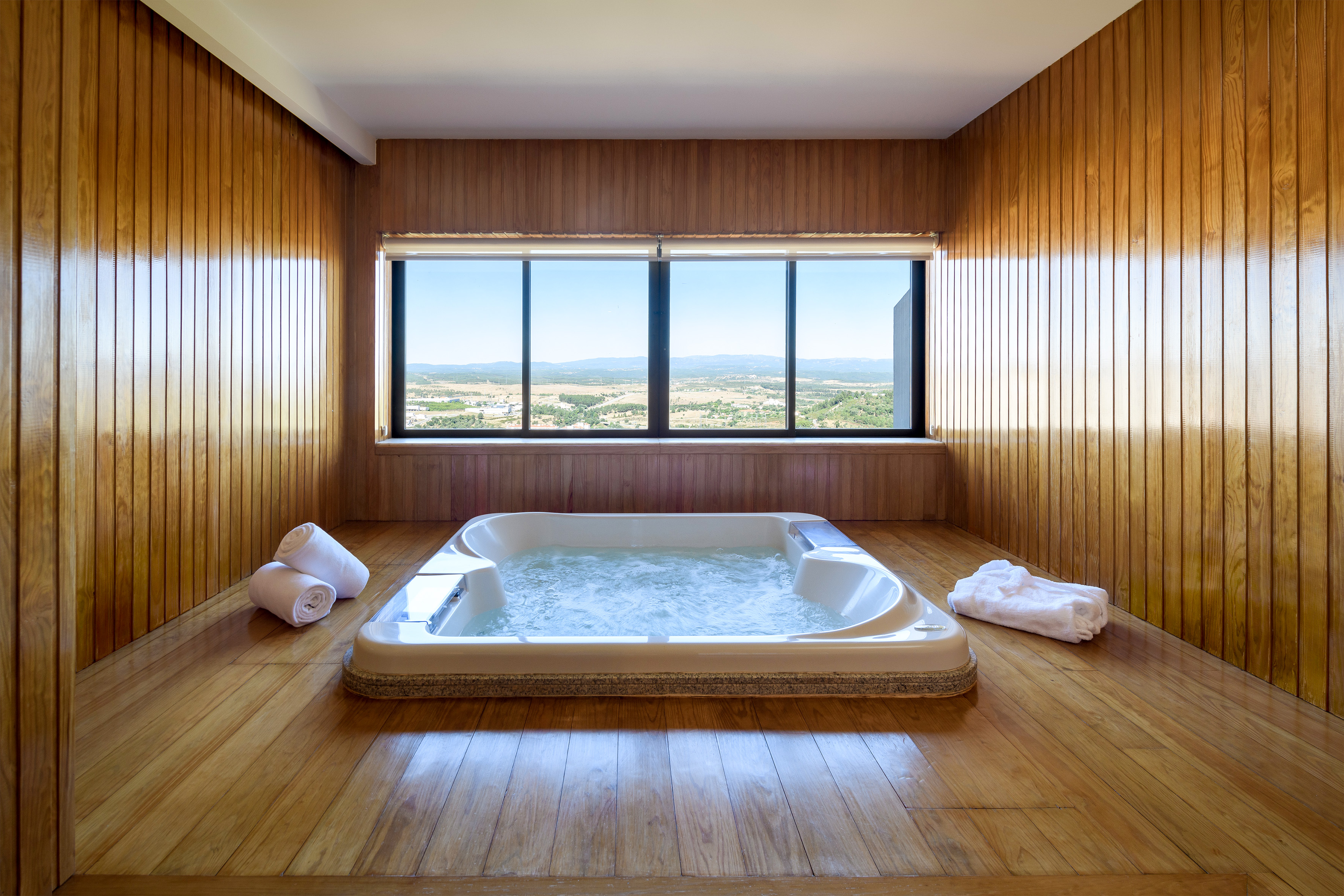 a large hot tub in a room with wood walls and windows
