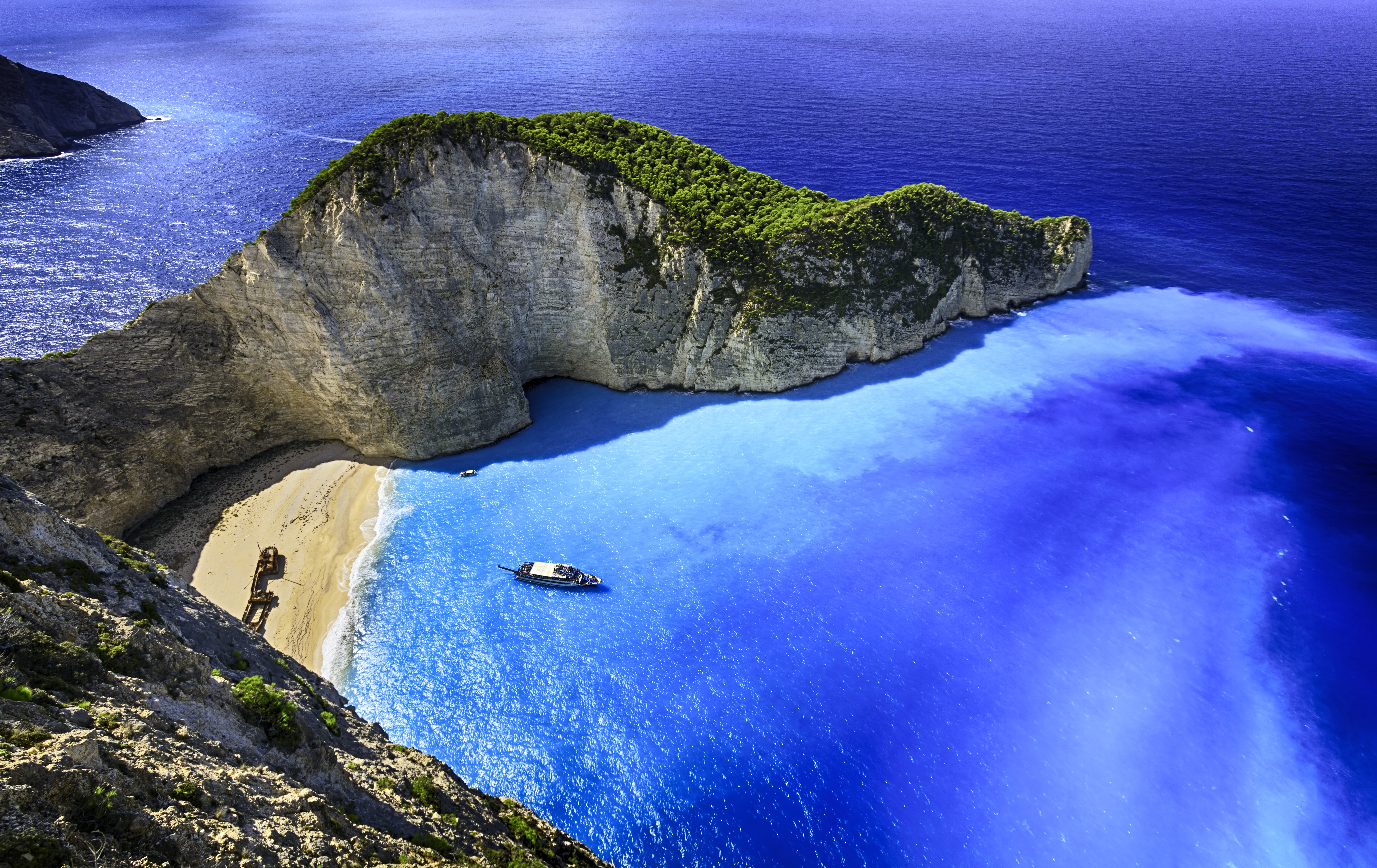 a large rock island with a boat on the beach