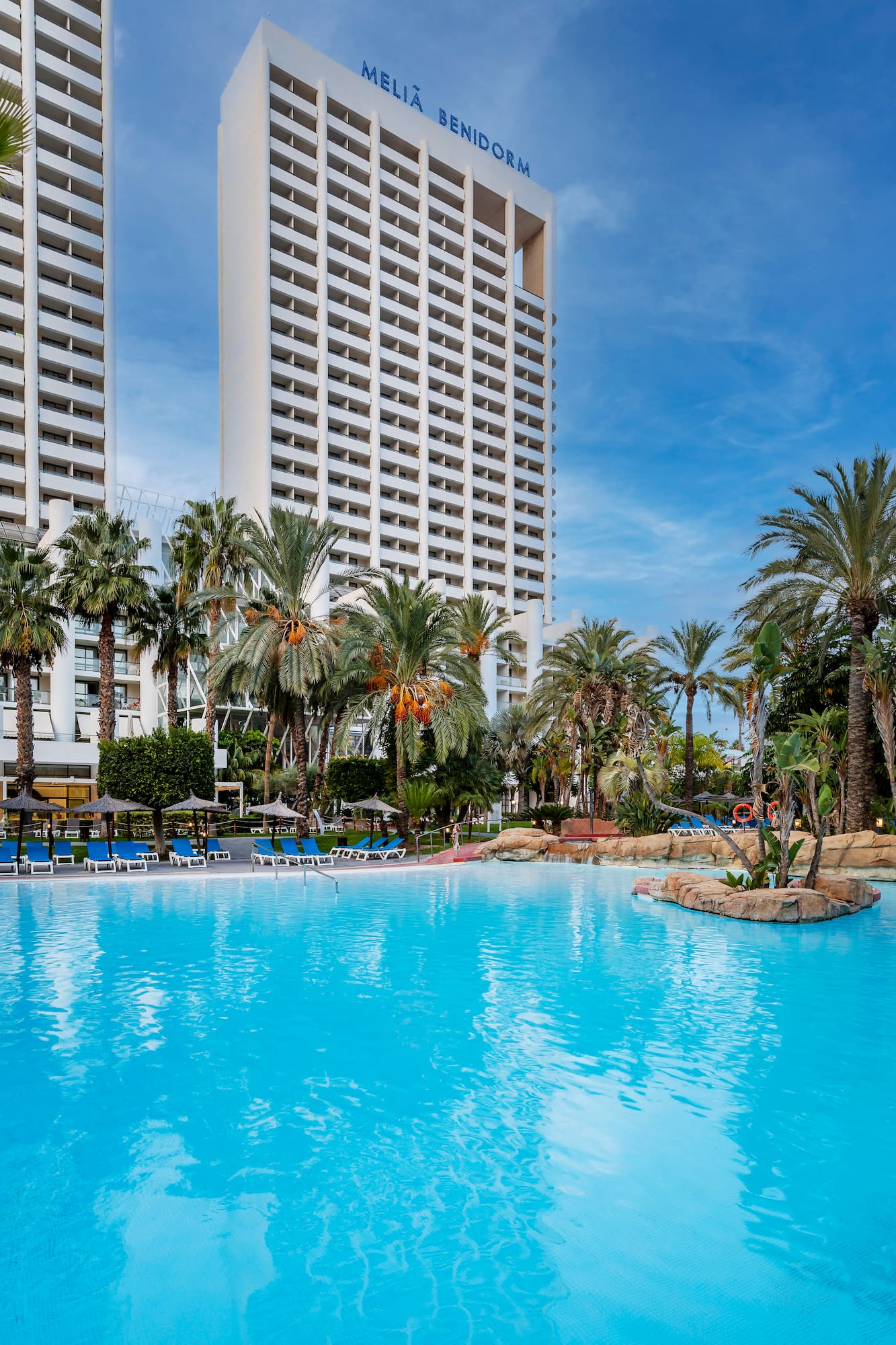 a pool with palm trees and a building in the background