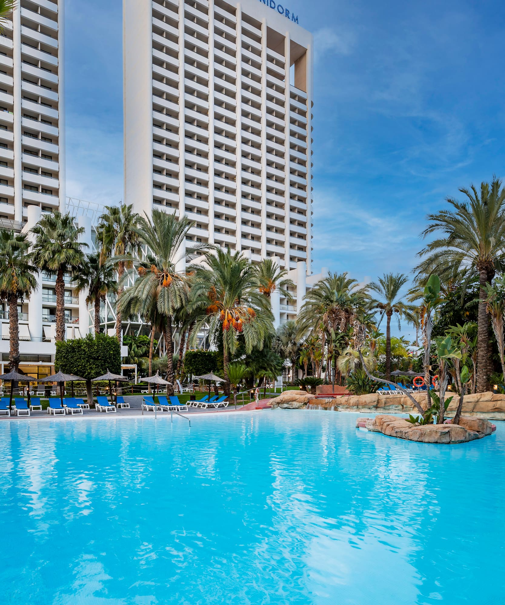 a pool with palm trees and a building in the background