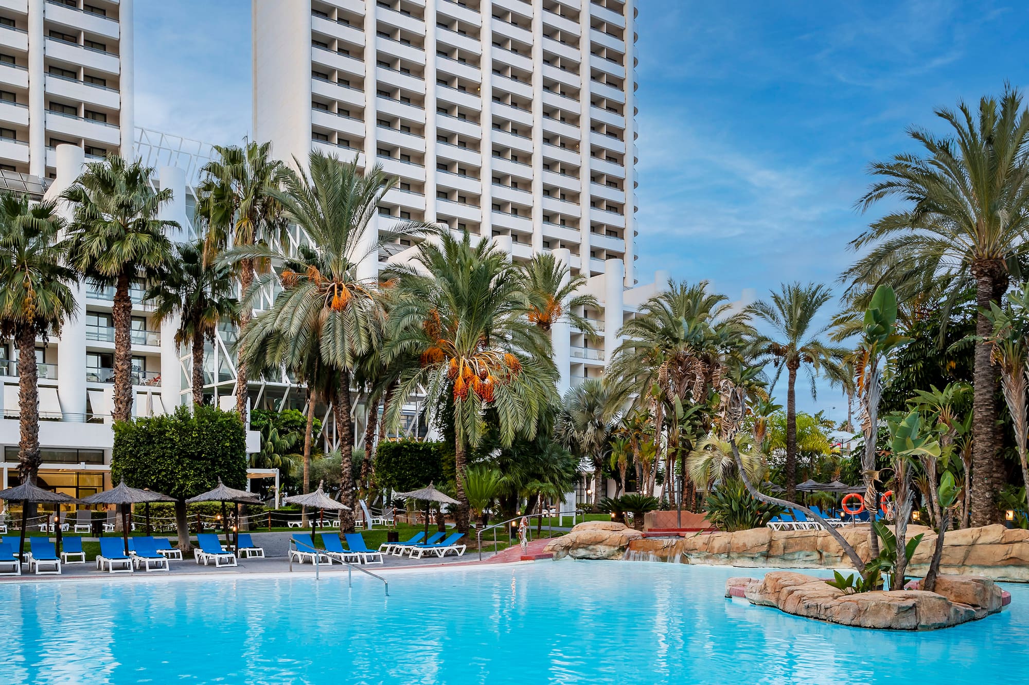 a pool with palm trees and a building in the background