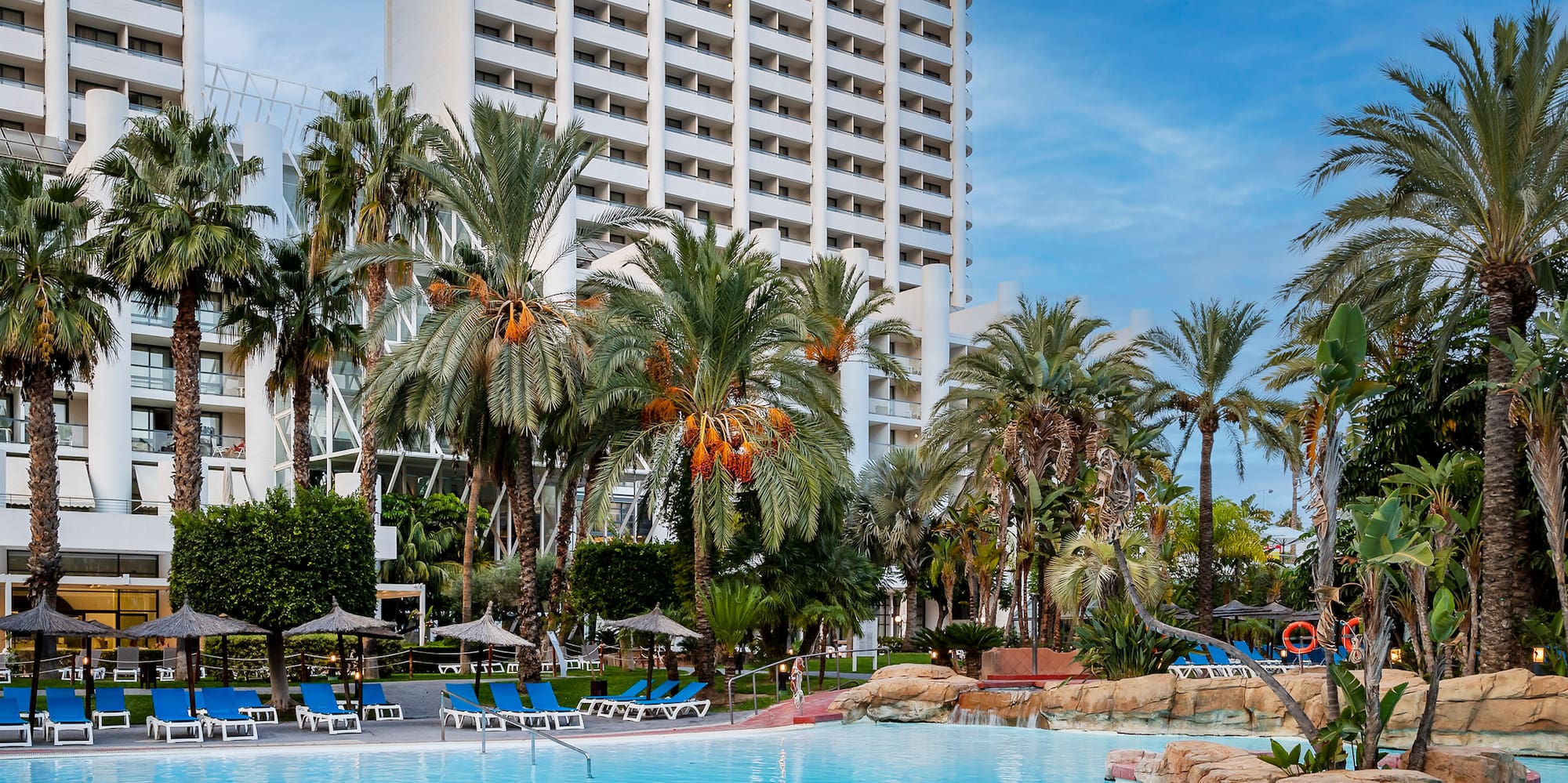 a pool with palm trees and a building in the background