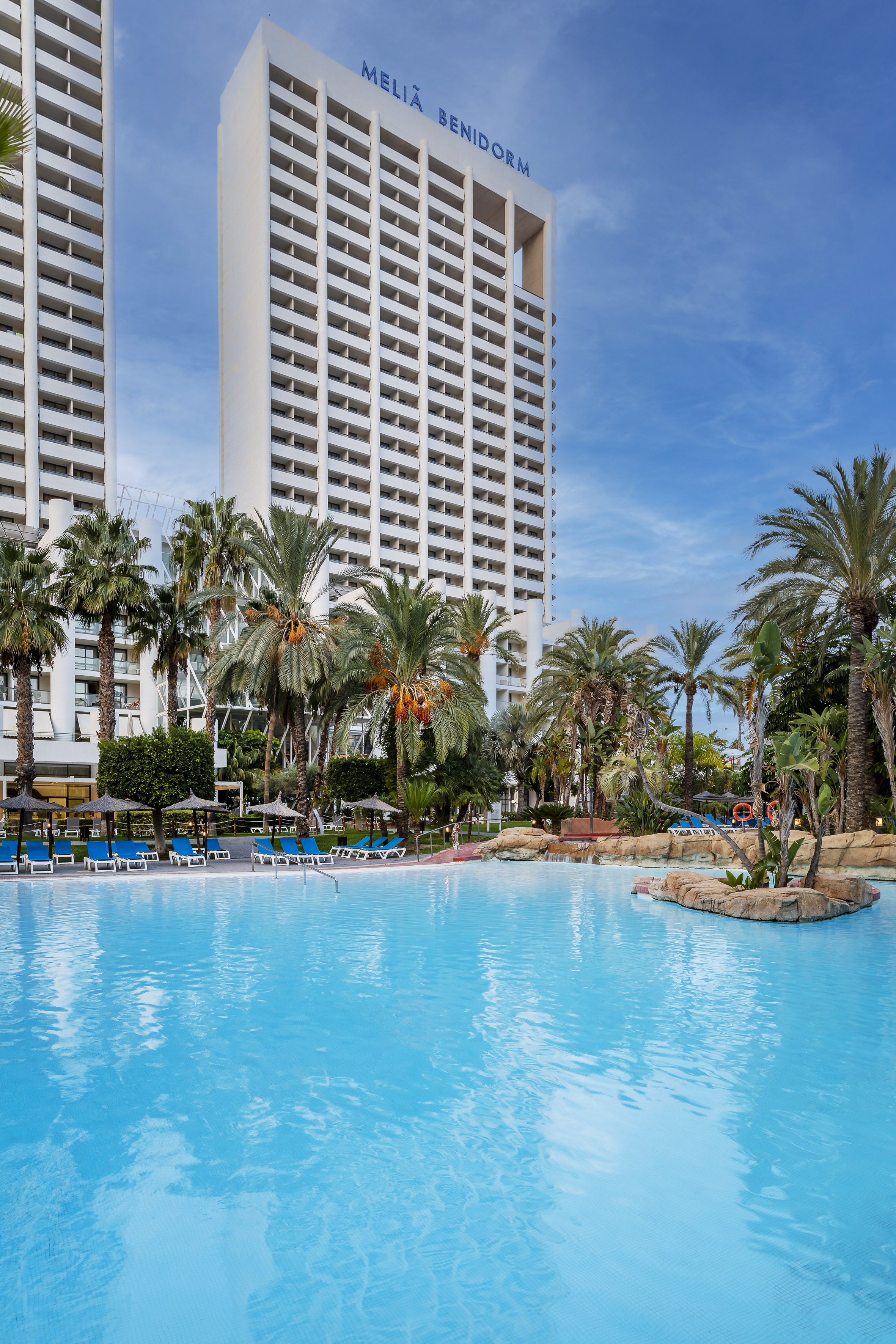 a pool with palm trees and a building in the background