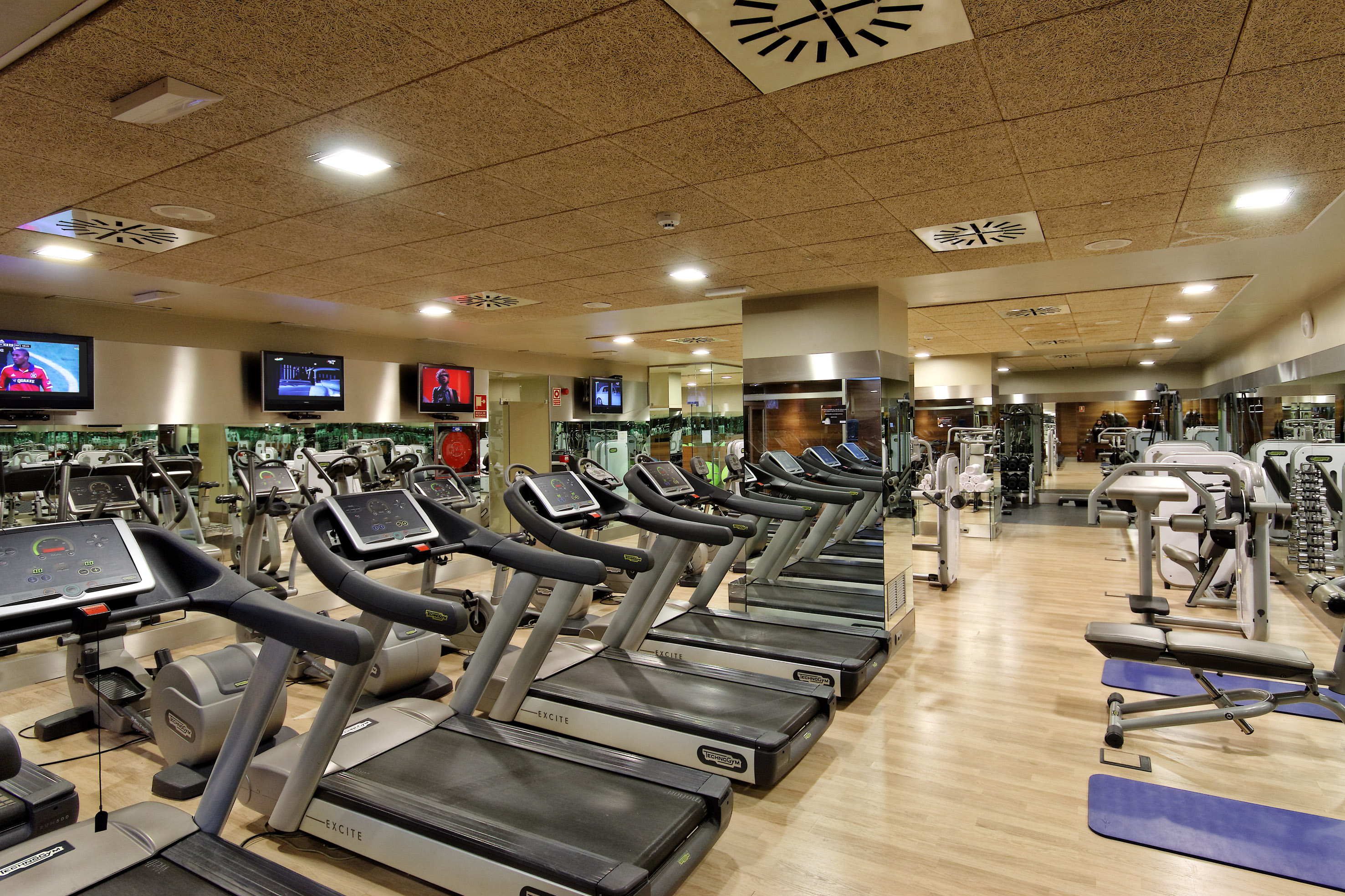 Fitness center featuring rows of treadmills, cardio machines, and strength equipment.