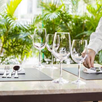 a person setting a table with wine glasses and a napkin