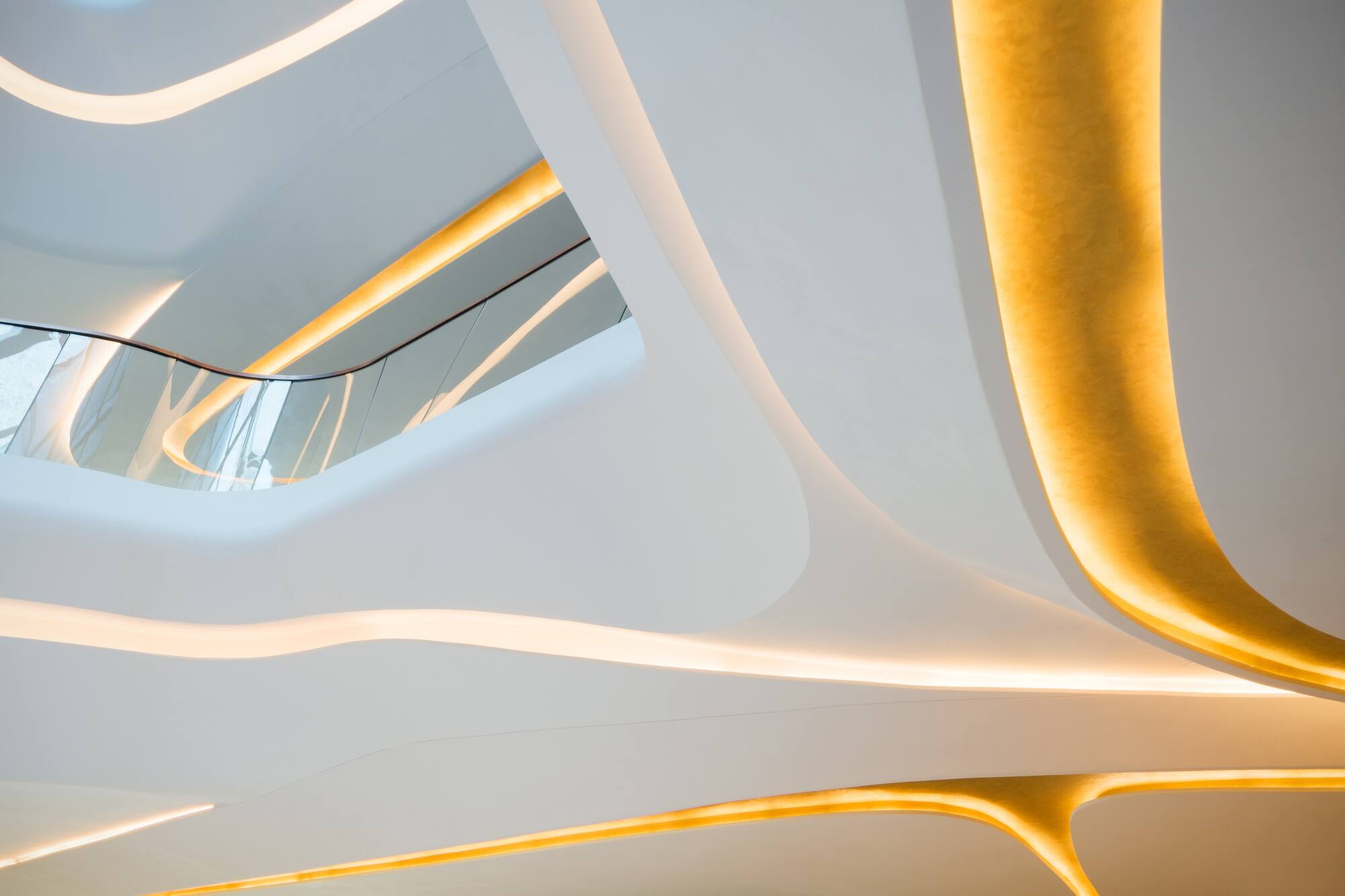 Modern interior with curved white architecture and golden LED strip lighting.