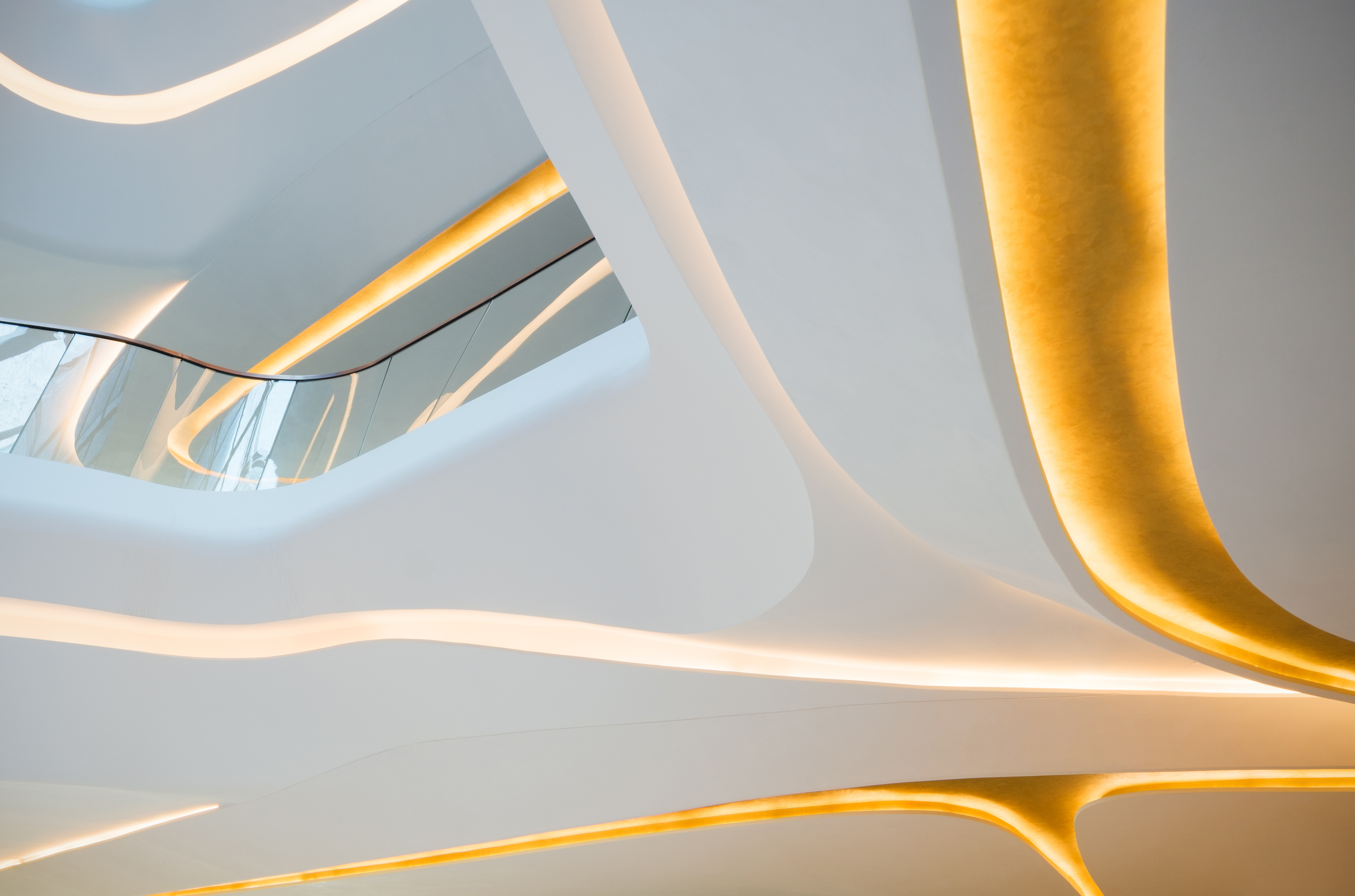 Modern interior with curved white architecture and golden LED strip lighting.
