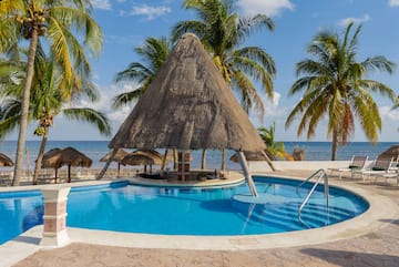 a pool with a straw roof and a bar and a beach