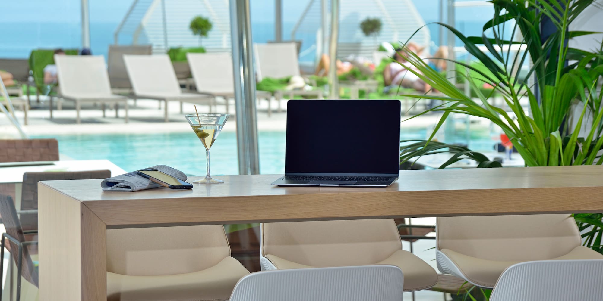 a laptop on a table with chairs and a martini glass