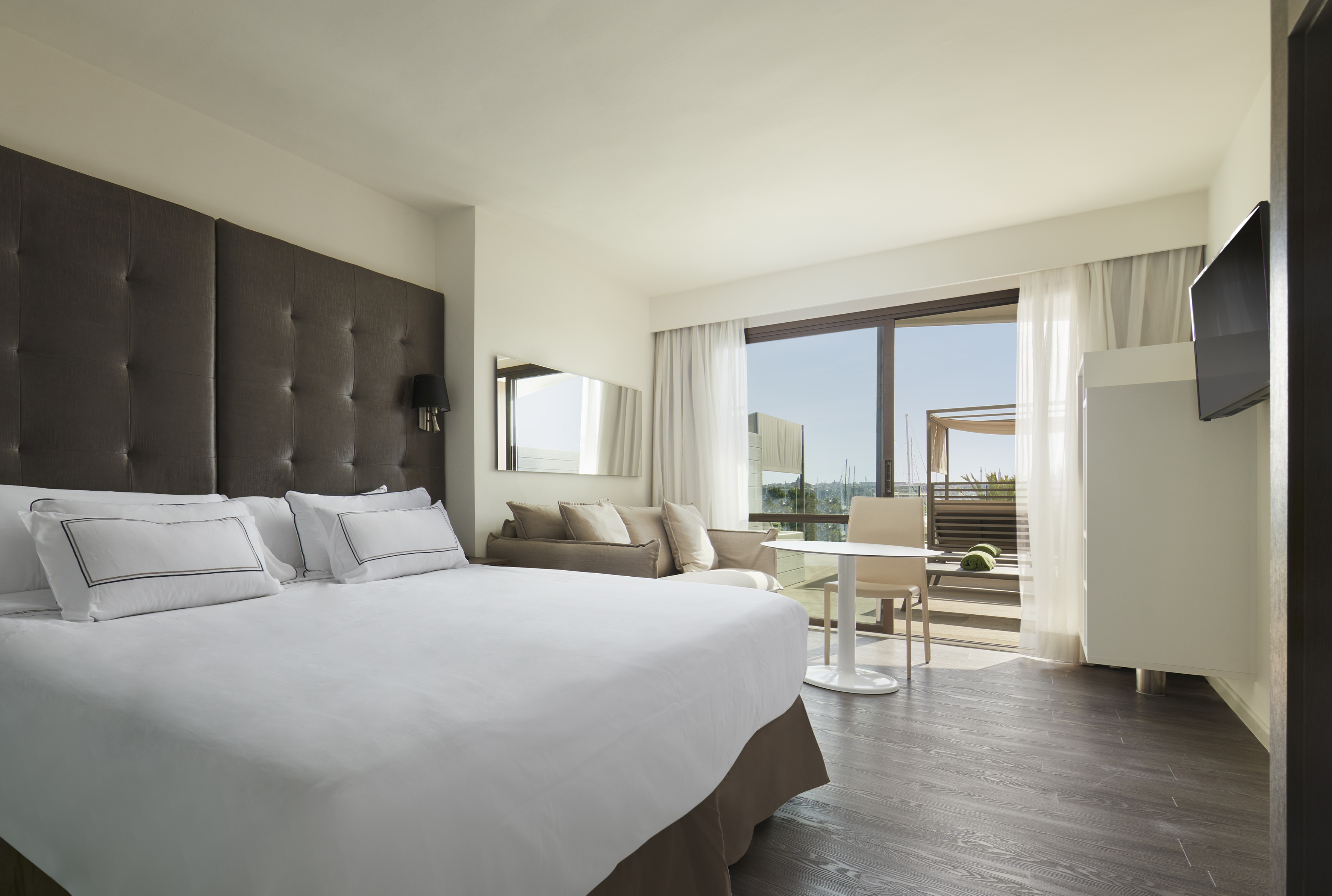Luxury hotel room with large bed, balcony access, and marina view.